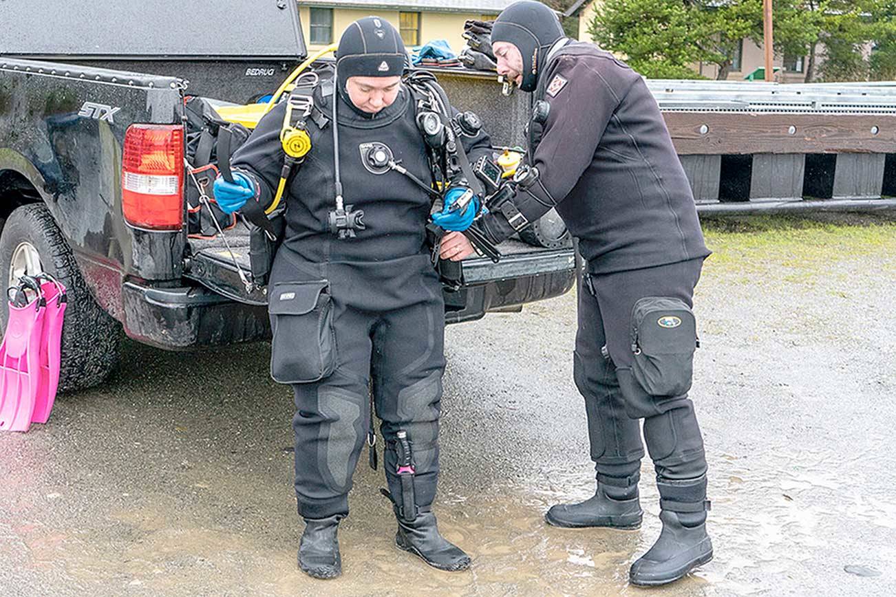 Matt Peaverly of Portland, Ore., helps his wife Grace with her dive gear before they go diving at the Marine Science Center at Fort Worden State Park on Monday. The couple, along with another diver, went diving at various sites during the weekend. (Steve Mullensky/for Peninsula Daily News)