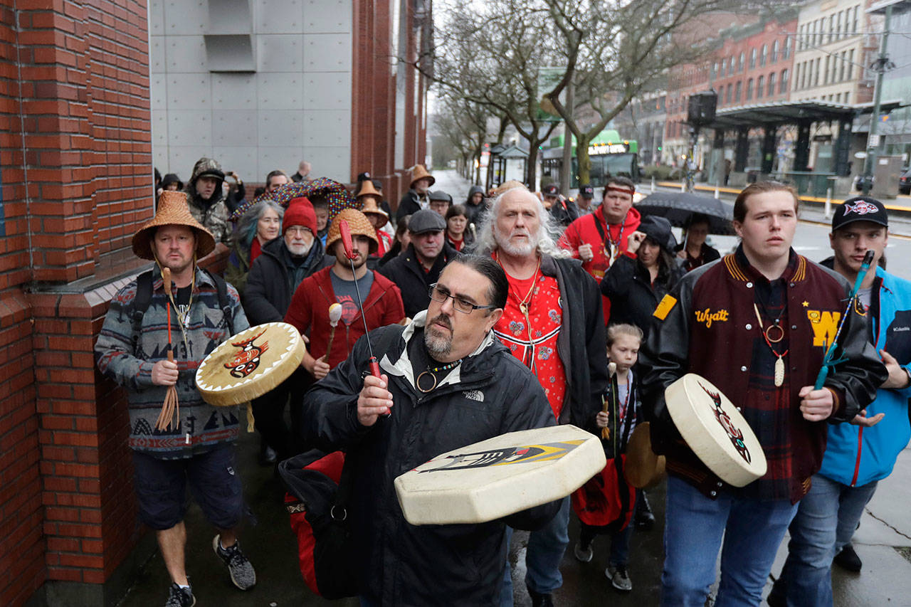 In this Jan. 6, 2020 photo, Tony A. (Naschio) Johnson, center, elected chairman of the Chinook Indian Nation, plays a drum as he leads tribal members and supporters as they march to the federal courthouse in Tacoma, as they continue their efforts to regain federal recognition. As COVID-19 disproportionately affects Native American communities, many tribal leaders say the pandemic poses particular risks to tribes without federal recognition. The Chinook Nation received some federal funding through a local nonprofit for small tribes to distribute food to elders and help with electricity bills, tribal Johnson said. (AP Photo/Ted S. Warren)