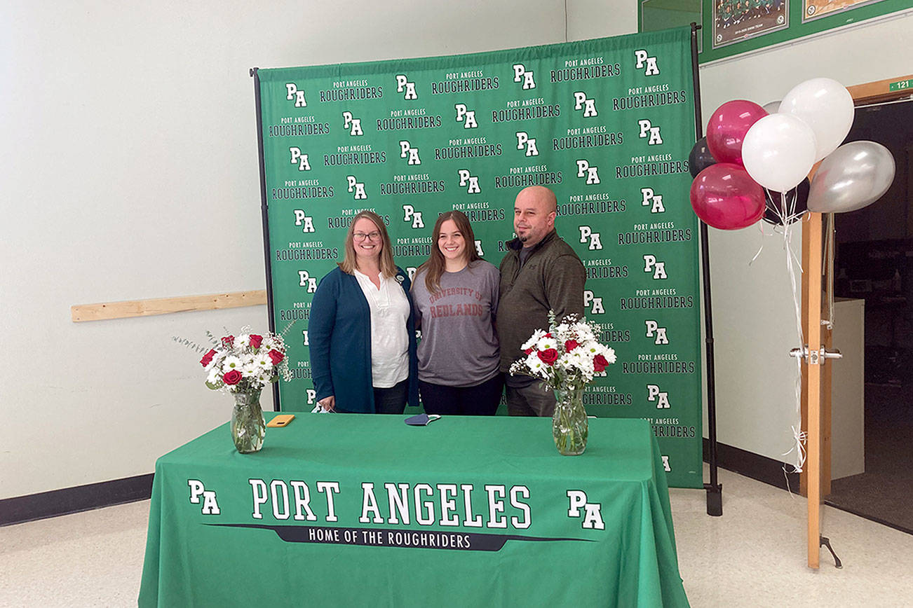 Port Angeles senior Katelyn Sheldon, center, is joined by her parents Melissa and Jeremy Sheldon after signing a letter of intent to compete for the University of Redlands track and field team. (Michael Carman/Peninsula Daily News)