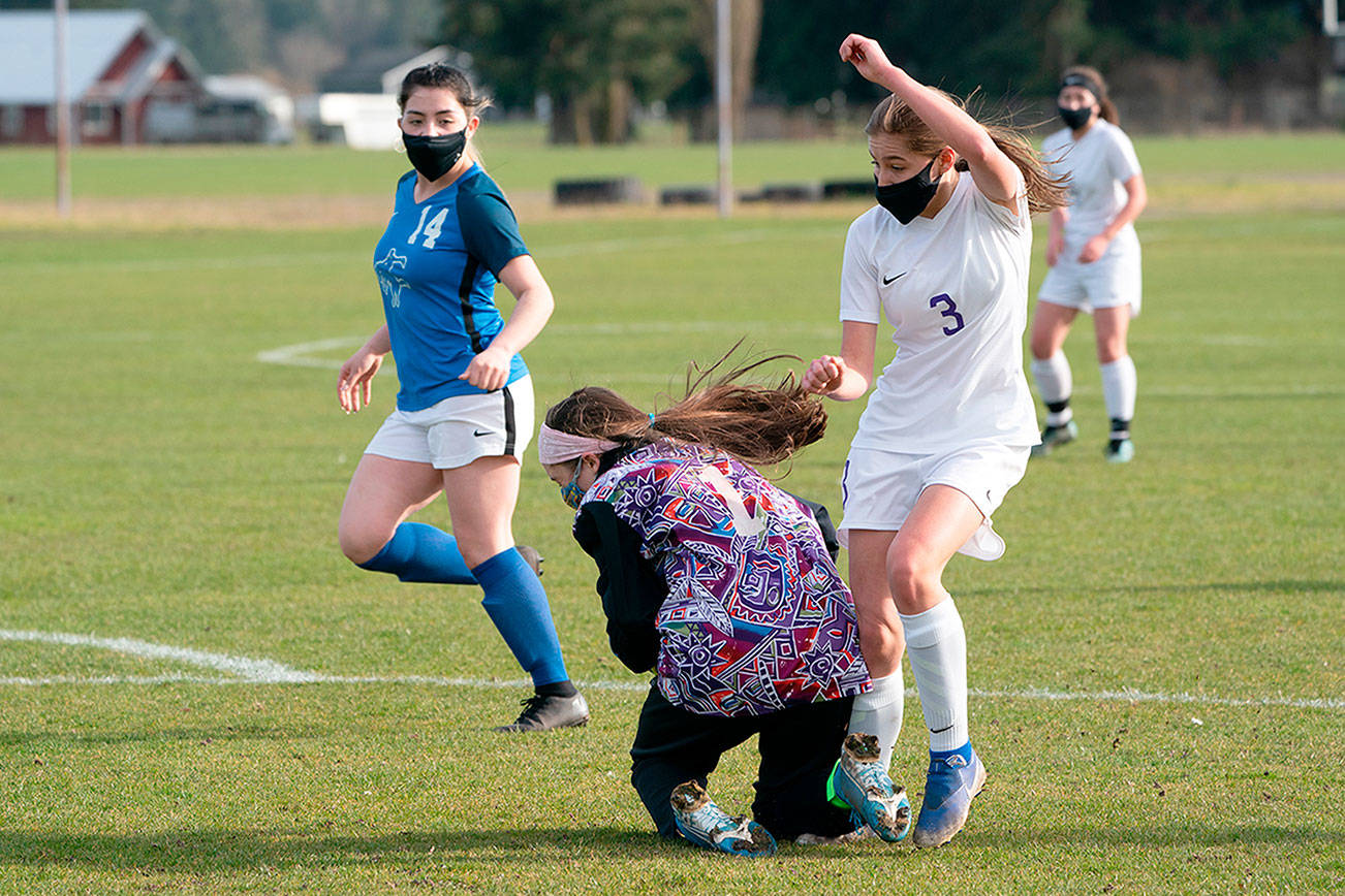 East Jefferson goalkeeper Sorina Johnston, center, saves a shot on goal but trips up Sequim's Taryn Johnson while covering the ball during a game on Wednesday in Chimacum. (Steve Mullensky/for Peninsula Daily News)