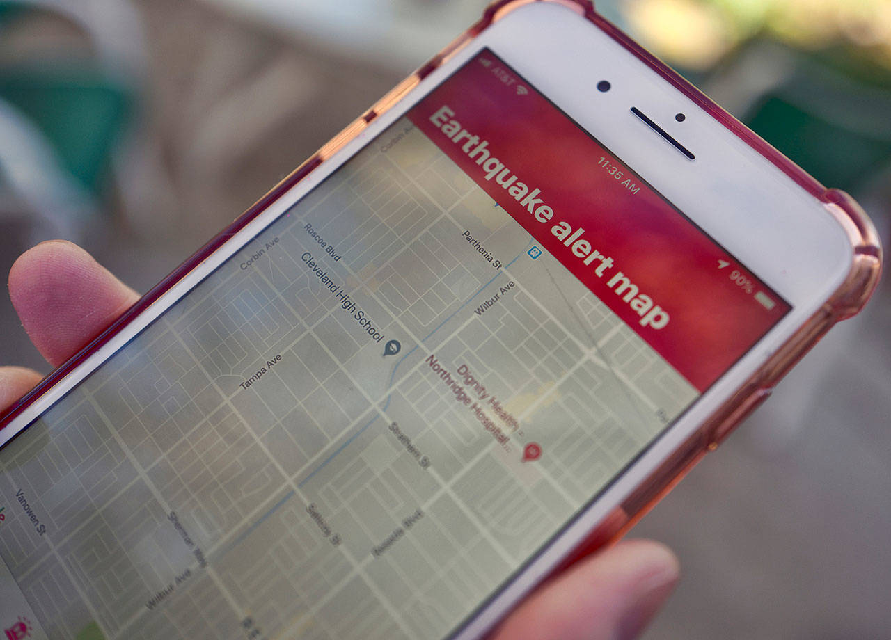 In this Jan. 3, 2019, file photo, a mobile phone customer looks at an earthquake warning application on an iPhone in Los Angeles. An earthquake early warning system operated by the U.S. Geological Survey has been activated in Oregon on the 10th anniversary of the devastating earthquake and tsunami in Japan. California already has the system. Washington state joins it in May, which will complete coverage of the West Coast of the contiguous United States. (Richard Vogel/The Associated Press, file)