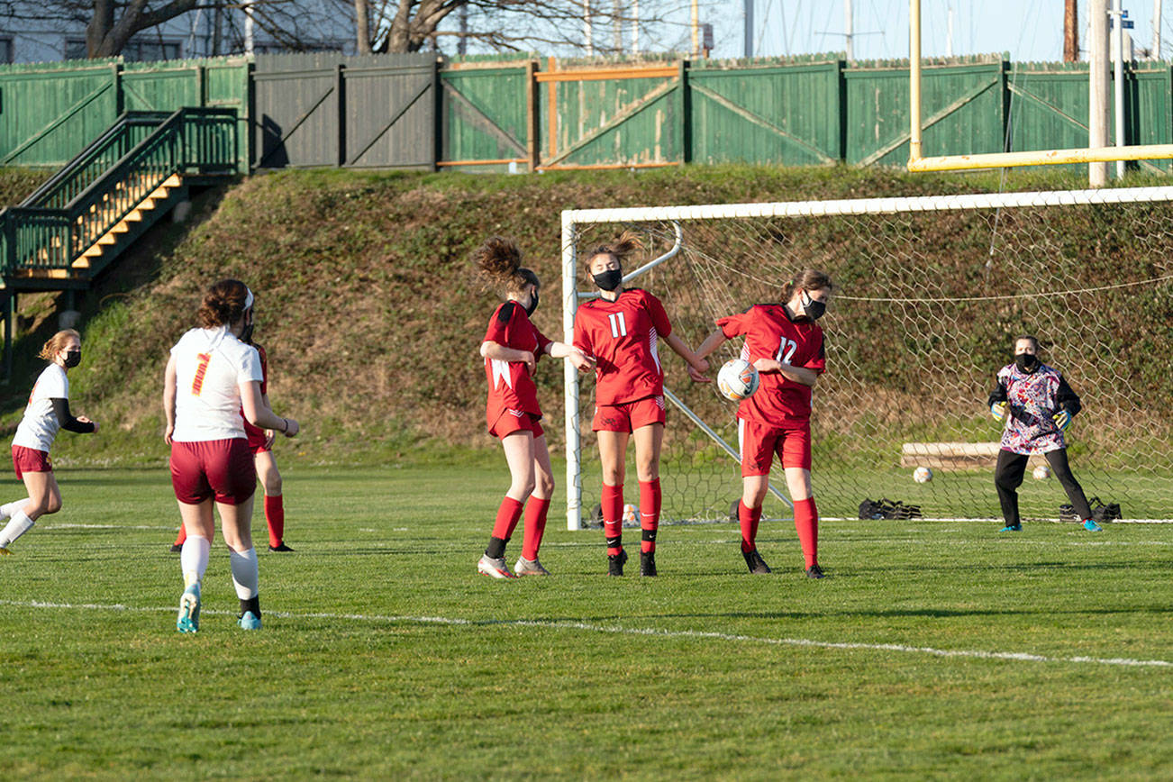 East Jefferson’s Aurin Asbell (12) takes a blow for the team by blocking a penalty kick from from the foot of Kingston’s Olivia Russell during a game at Port Townsend’s Memorial Field on Tuesday. Stand with Aurin are Leah Harrison, (1) and Iris Mattern (11) during a game in Port Townsend on Tuesday. (Steve Mullensky/for Peninsula Daily News)