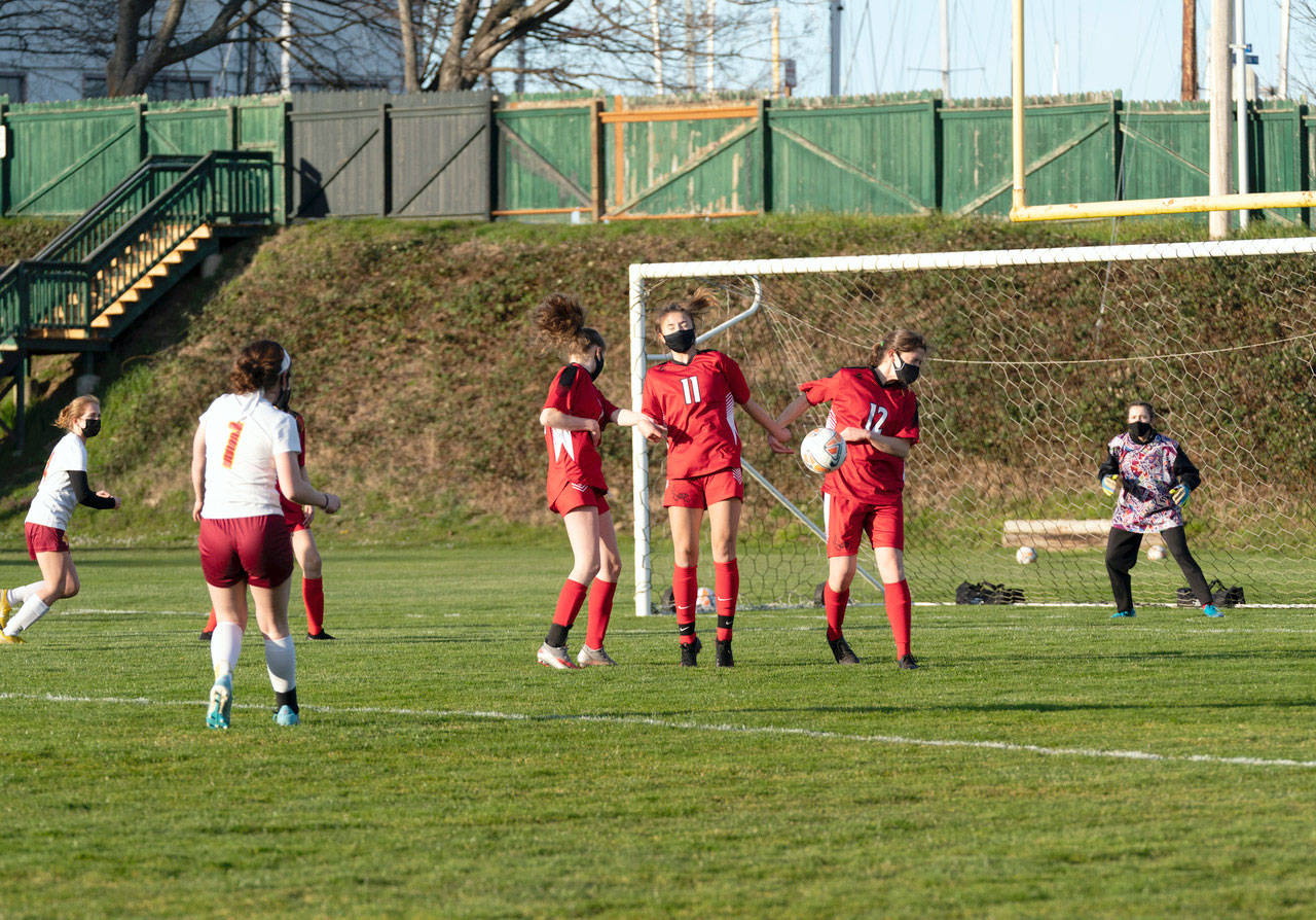 East Jefferson’s Aurin Asbell (12) takes a blow for the team by blocking a penalty kick from from the foot of Kingston’s Olivia Russell during a game at Port Townsend’s Memorial Field on Tuesday. Stand with Aurin are Leah Harrison, (1) and Iris Mattern (11) during a game in Port Townsend on Tuesday. (Steve Mullensky/for Peninsula Daily News)