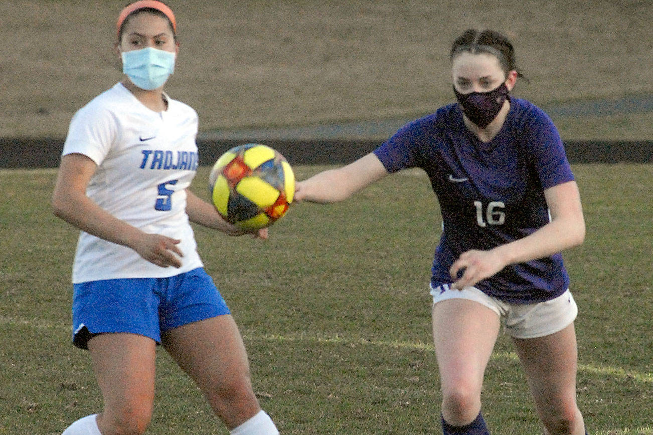 Olympic’s Alexis Valenzuela, left, and Sequim’s Abigail Schroeder chase after a loose ball during Tuesday night’s match at Sequim High School. (Keith Thorpe/Peninsula Daily News)