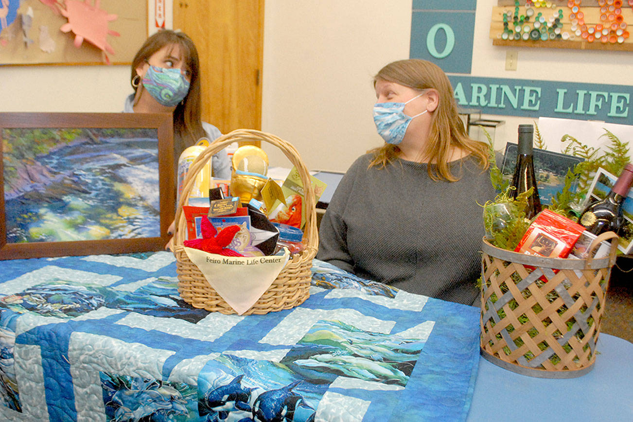 <strong>Keith Thorpe</strong>/Peninsula Daily News
 Feiro Marine Life Center Development Director Linty Hopie, left, and Executive Director Melissa Williams sit with some of the auction items to be sold at the center’s Making Waves 2021: Resilience online fundraising event.