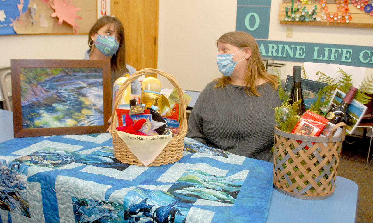 <strong>Keith Thorpe</strong>/Peninsula Daily News
 Feiro Marine Life Center Development Director Linty Hopie, left, and Executive Director Melissa Williams sit with some of the auction items to be sold at the center’s Making Waves 2021: Resilience online fundraising event.