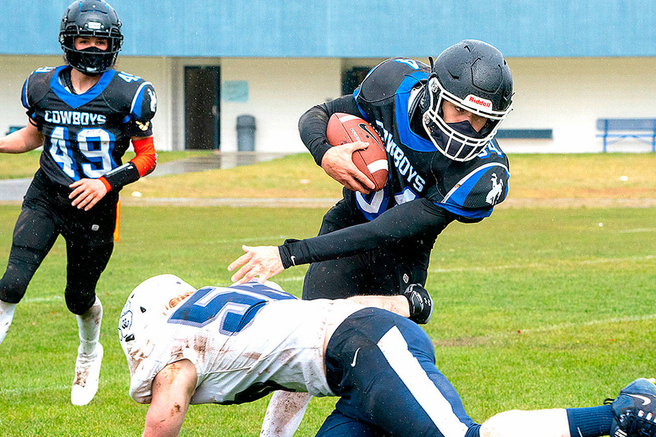 Steve Mullensky/for Peninsula Daily News
East Jefferson’s Lonnie Kenney (49) watches as teammate Logan Massie (34) pivots around Cascade Christian’s Ryan Hersey to pick up yardage in a game played in Chimacum on Saturday.