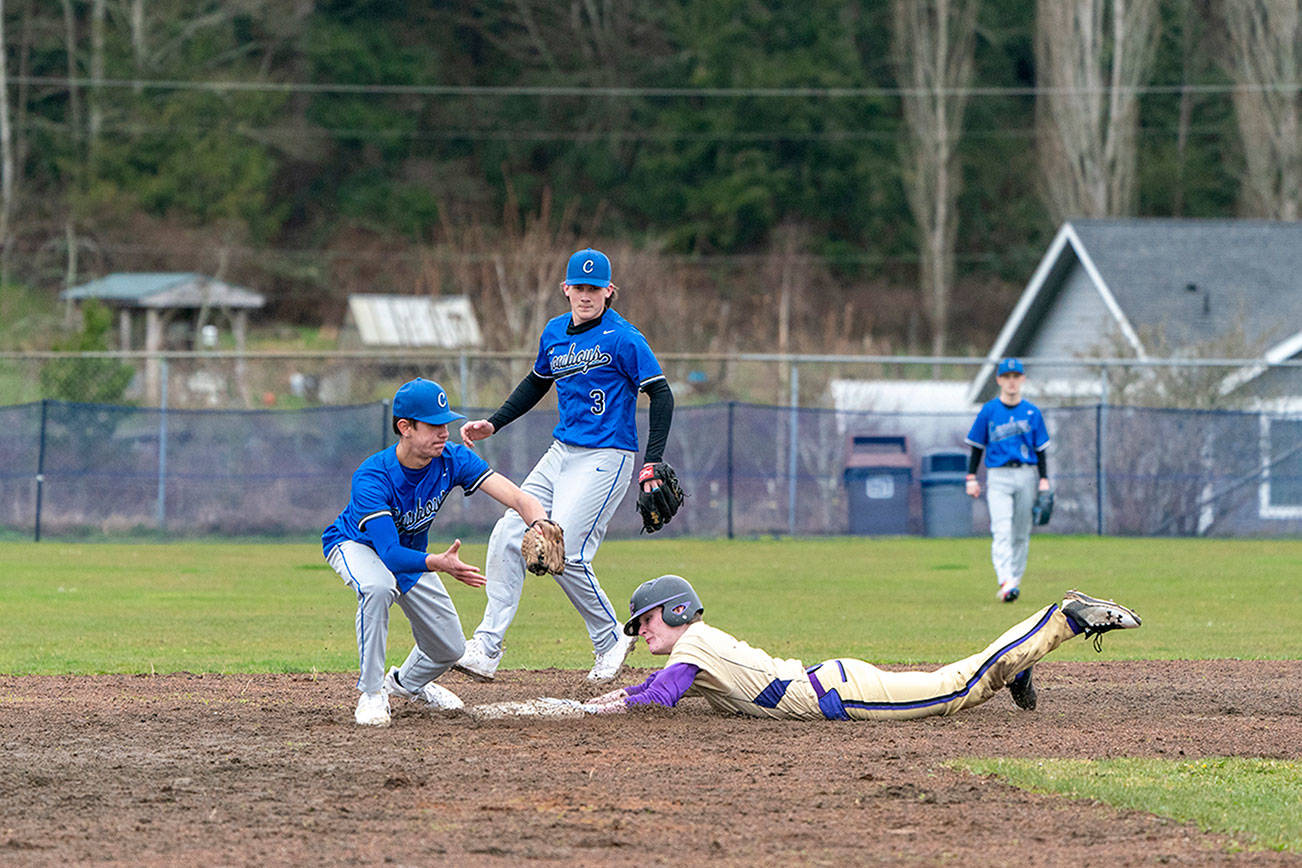 Steve Mullensky/for Peninsula Daily News

Sequim’s Ryan Porter slides safely into second under the glove of East Jefferson’s Hunter Cerna during a rainy Wednesday afternoon game played in Chimacum. Poised to back-up the play is Marcus Ritch, (3).