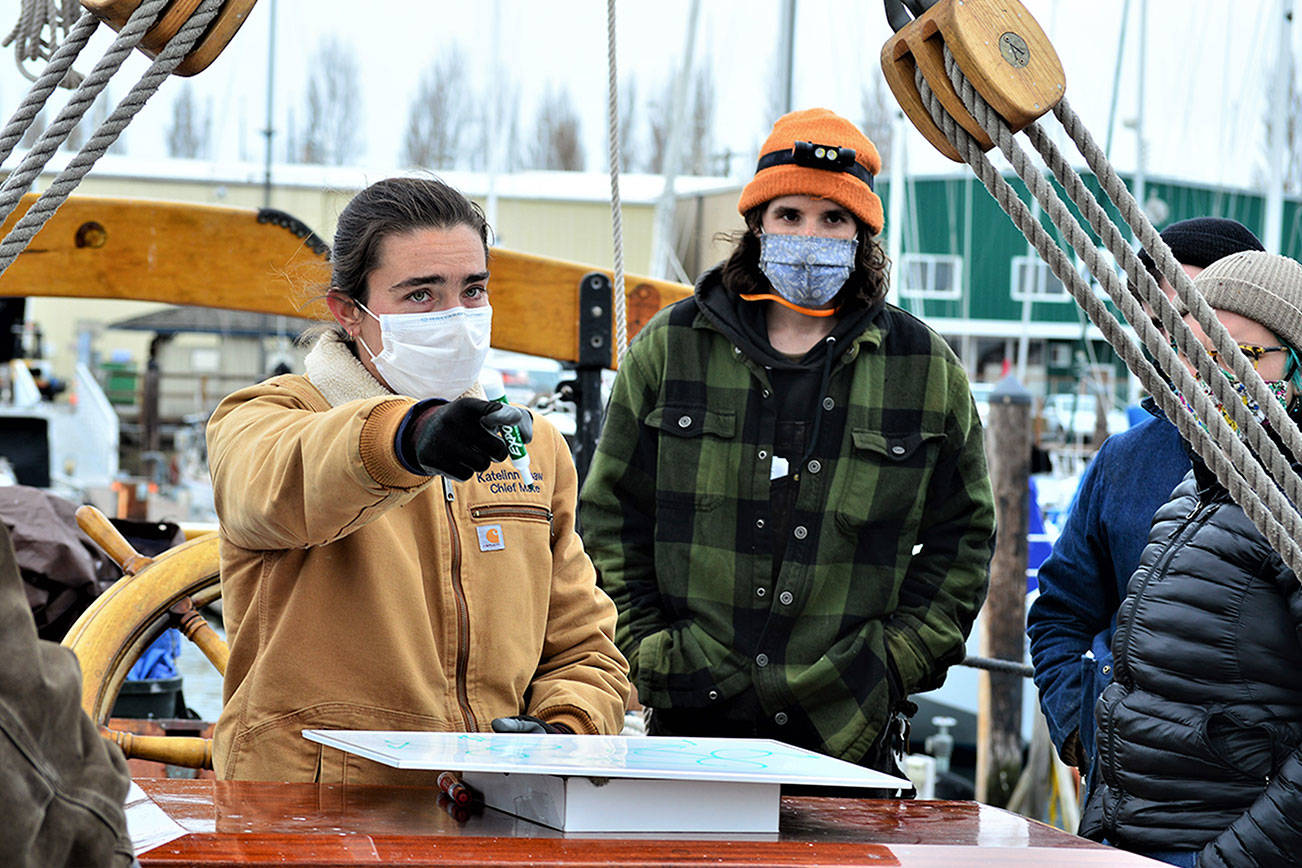 Adventuress Capt. Katelinn Shaw discusses steering and navigation with Northwest School of Wooden Boatbuilding students including Drew Harman, right, on board the schooner. (Diane Urbani de la Paz/Peninsula Daily News)