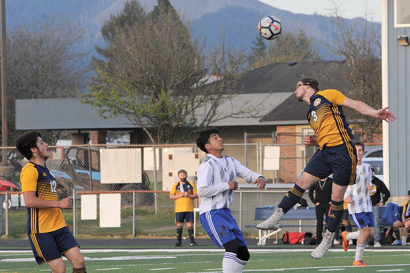 Lonnie Archibald/for Peninsula Daily News
Forks defender Colton Duncan heads the ball away during the Spartans win over Elma while Spartan Luis Torres (12) looks on.