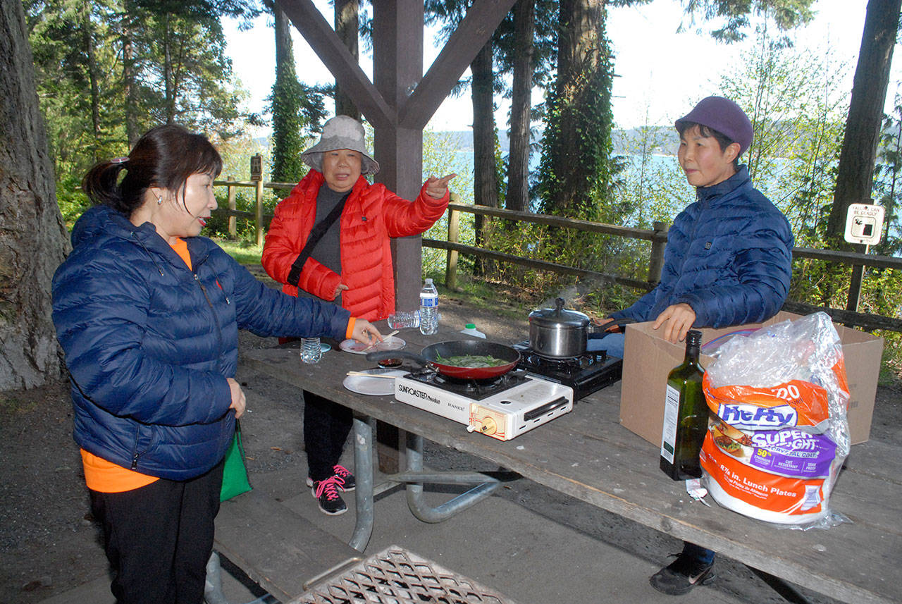 Young Hanson of Dallas, left, along with Chun Kim and Jennifer Choi, both of Tacoma, prepares lunch at a picnic shelter at Sequim Bay State Park east of Sequim on Thursday. The group took advantage of a free day at all state parks in celebration of Earth Day. The next free state parks day will be June 5 to celebrate National Trails Day. (Keith Thorpe/Peninsula Daily News)