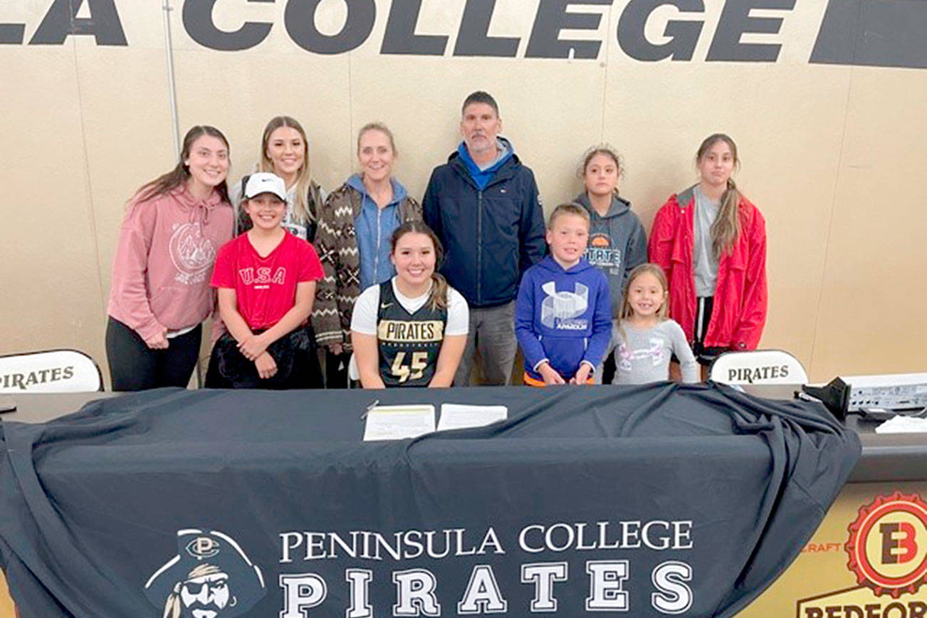 Neah Bay's Ruth Moss, seated wearing No. 45, is joined by her family, including parents Robert and Cinnamon Moss, as she signs a letter of intent to play basketball at Peninsula College.