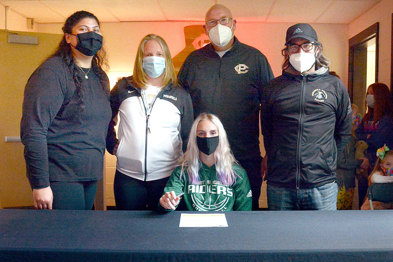 Port Angeles' Millie Long, seated, prepares to sign her letter of intent to play soccer and basketball for Peninsula College. She is joined by, from left, Peninsula College women's basketball assistant coaches Gabi Fenumiai and Mike Knowles, head coach Alison Crumb and women's soccer head coach Kanyon Anderson. (Peninsula College Athletics)