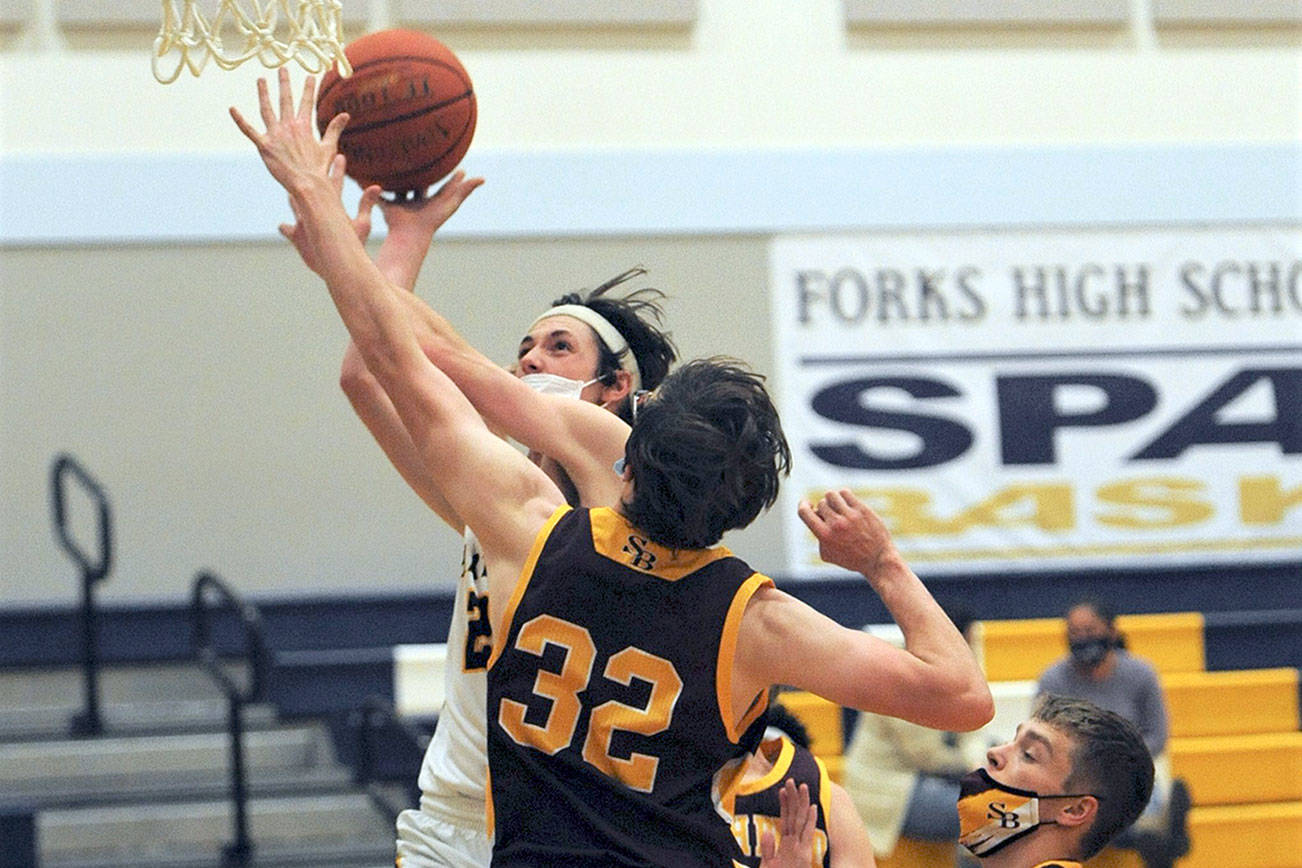 Forks' Raymond Davis scores over South Bend's Steven Kirpes during the Spartans' 84-30 Pacific League win over the Indians. Davis had 12 points in the game. (Lonnie Archibald/for Peninsula Daily News)