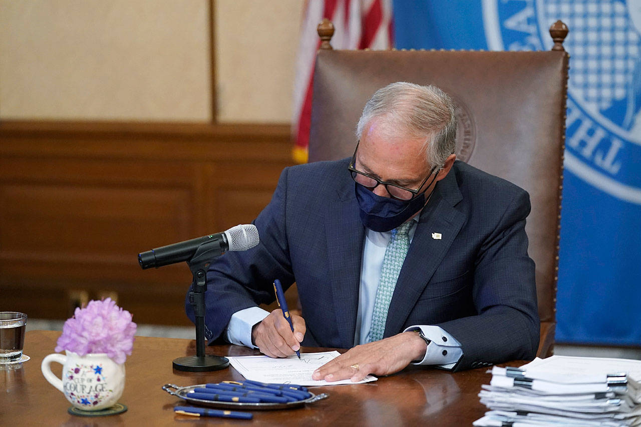 Gov. Jay Inslee signs a bill into law Wednesday at the Capitol in Olympia that prohibits openly carrying guns and other weapons at the state Capitol and protests statewide. (Ted S. Warren/The Associated Press)