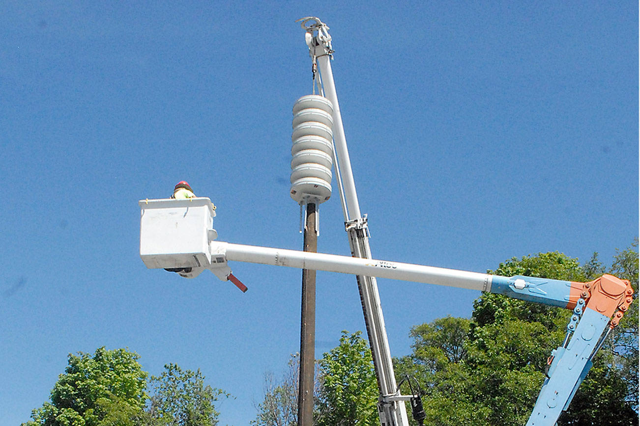 Keith Thorpe/Peninsula Daily News
A crew hoists a new tsunami siren into place atop a pole located in the public parking lot at First and Lincoln streets in downtown Port Angeles.