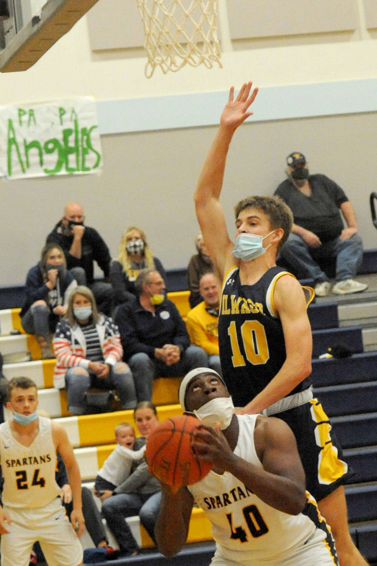 Forks’ Trey Baysinger (40) eyes the basket while Ilwaco’s Jaden Turner goes over his back and commits a foul during the Spartans’ 57-50 Pacific League win. (Lonnie Archibald/for Peninsula Daily News)