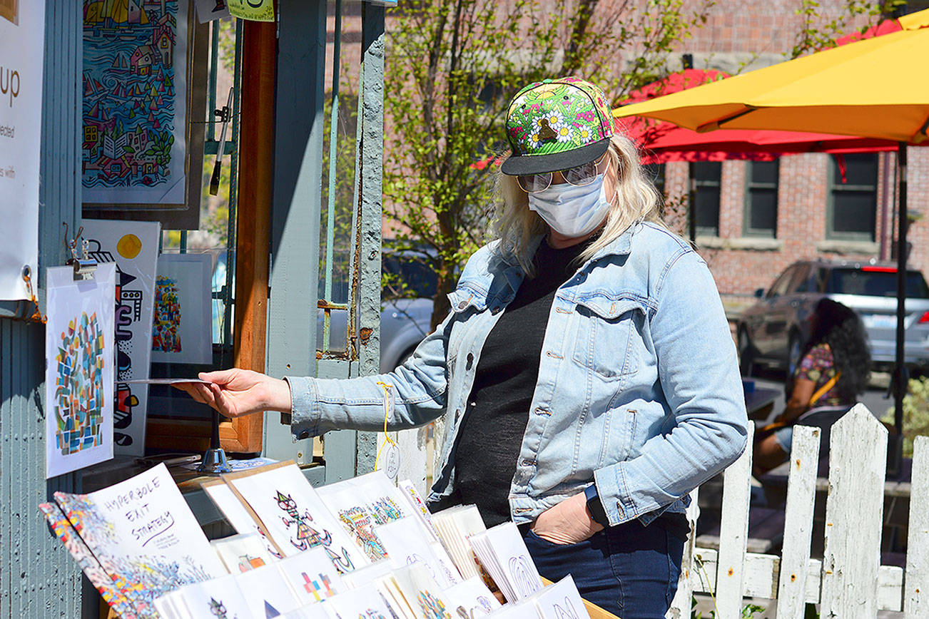 Bonnie Romani of Ocean Shores admires Mike Biskup's outdoor art gallery in downtown Port Townsend. Biskup and his work appear each weekend at the foot of Water Street.   Diane Urbani de la Paz/Peninsula Daily News