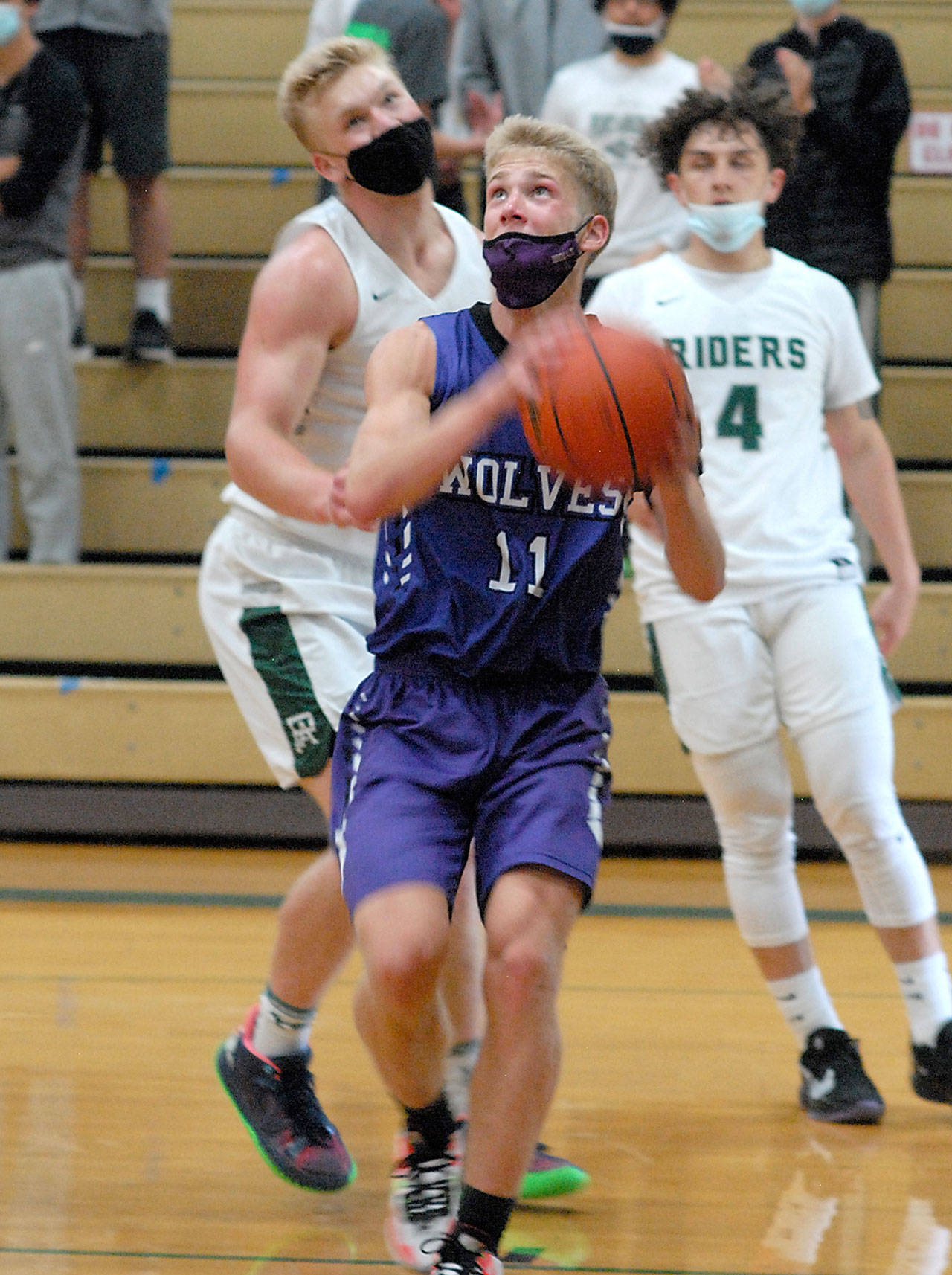 Keith Thorpe/Peninsula Daily News Sequim’s Erik Christiansen, front, looks for the hoops as Port Angeles’ Adam Watkins, left, and Jeremiah Hall look on during Saturday’s matchup at Port Angles High School.