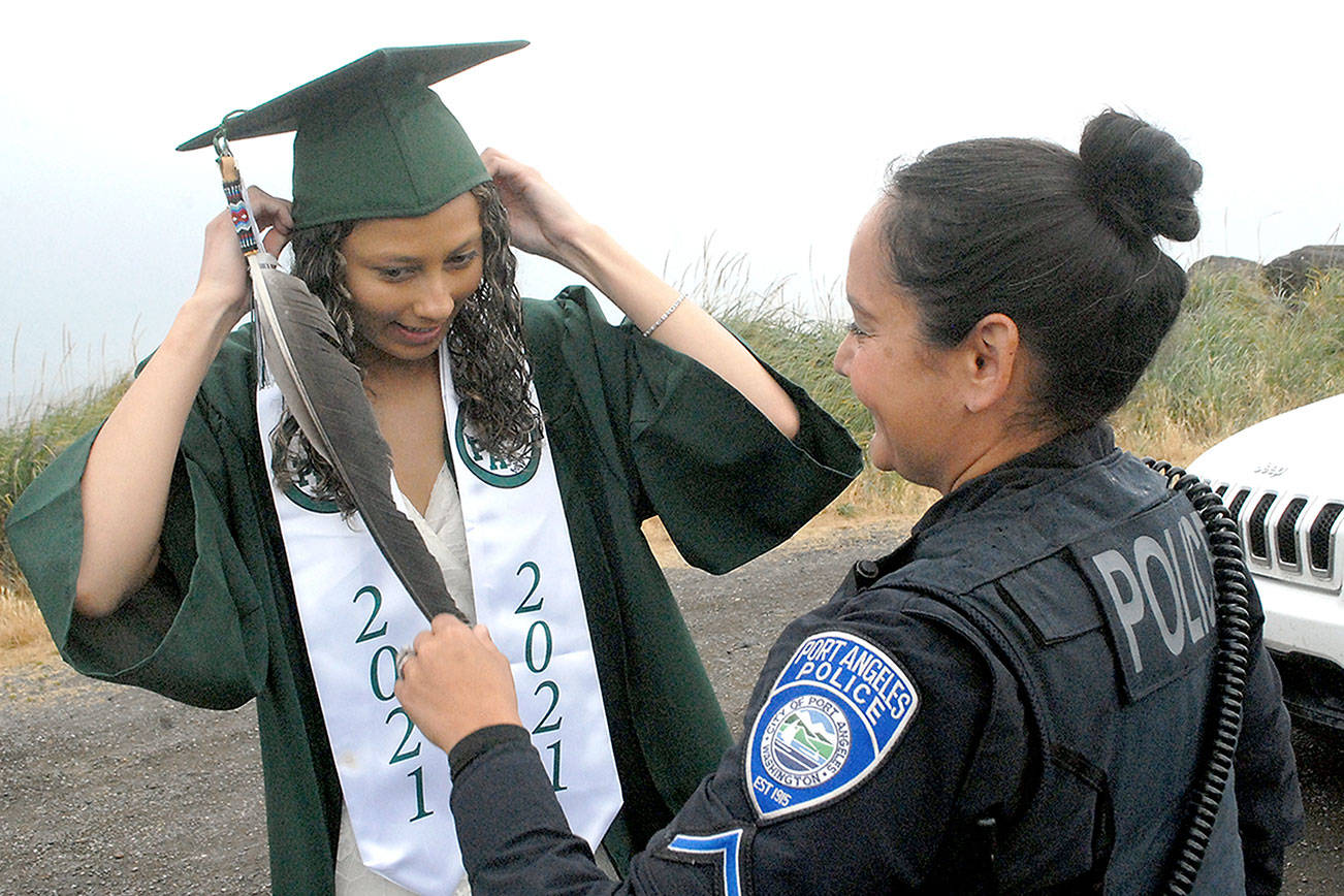 Keith Thorpe/Peninsula Daily News
Port Angeles High School graduate Kayanna Cordero gets assistance with her mortarboard from her mother, Port Angeles police Resource Officer Swift Sanchez, prior to the start of Friday's Senior Parade from Ediz Hook to the area of Port Angeles High School. Dozens of cars filled with grads and their families took part the procession - an activity started last year when COVID-19 cancelled the regular graduation ceremony. A total of 225 seniors were eligible for diplomas as the Class of 2021.