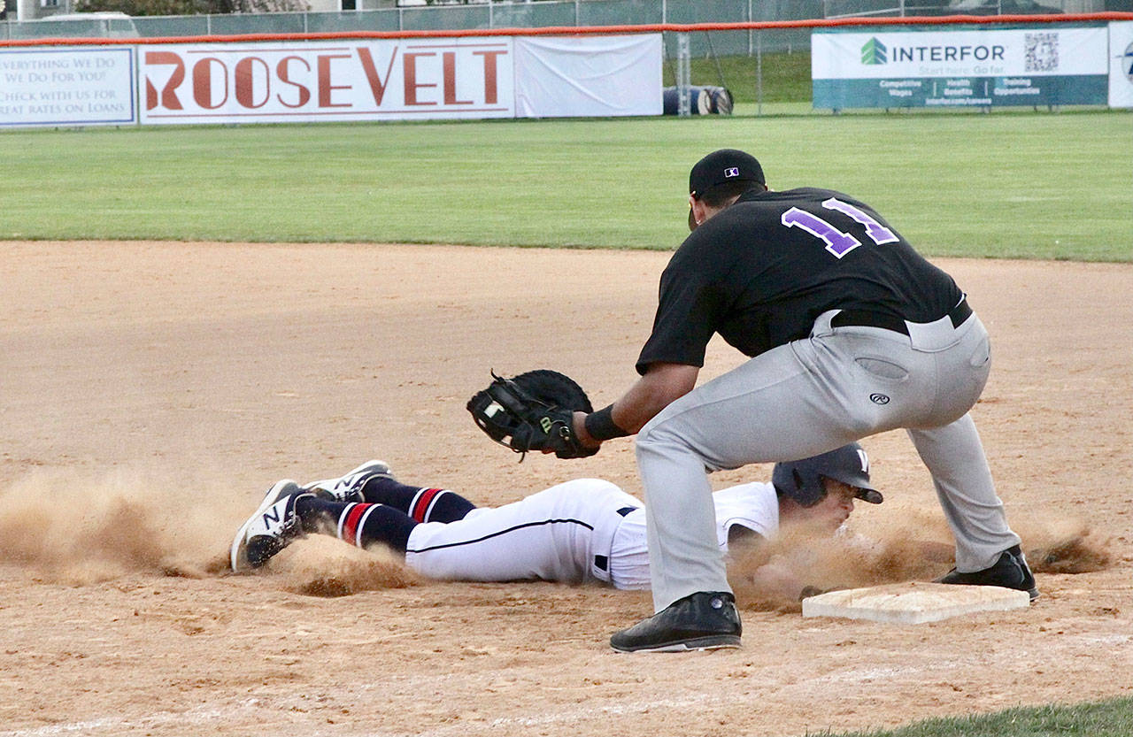 Wilder Senior’s Michael Grubb dives safely back to the first-base bag on a pickoff attempt as Seattle Select’s Alex Ballot prepares to apply the tag during an American Legion game Monday at Civic Field. (Dave Logan/for Peninsula Daily News)