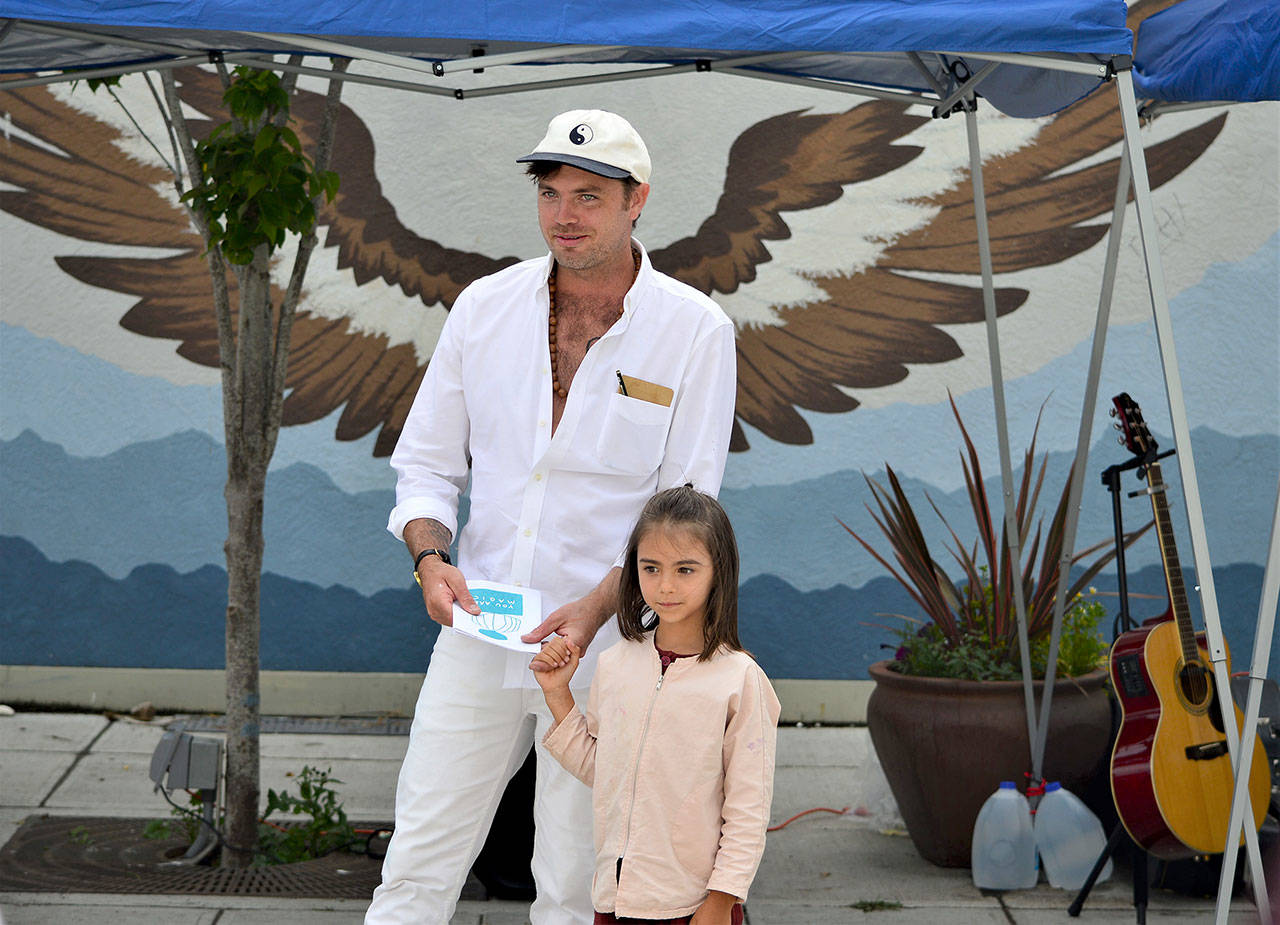 Sculptor Jonah Trople and his artist’s assistant and daughter Tula, 5, made an appearance Tuesday at the Tyler Plaza, where one of his Creative District art markers stands. (Diane Urbani de la Paz/Peninsula Daily News)