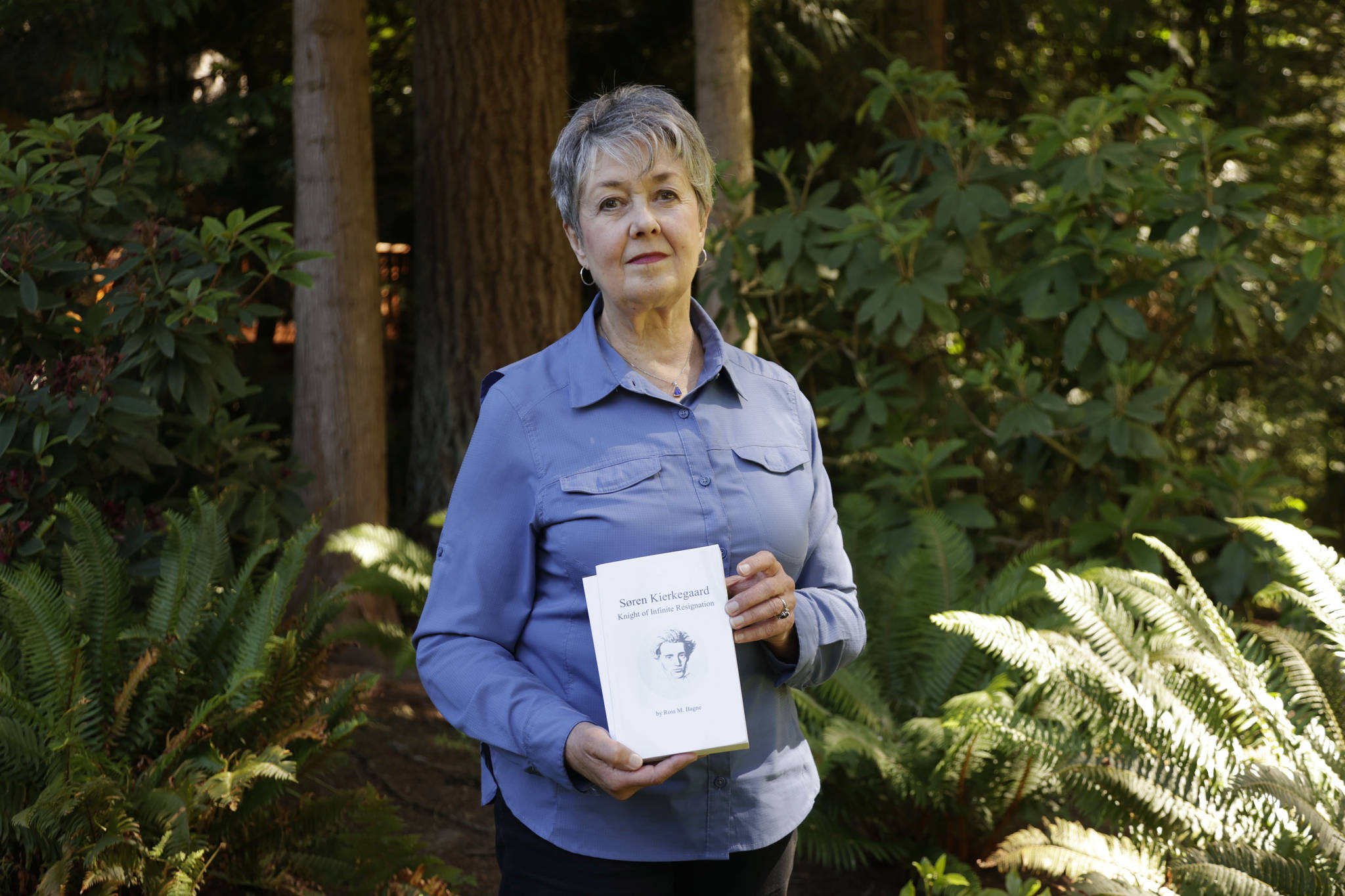 Karen McKnight stands in her backyard on June 19 in Sammamish, holding two books written by her brother, Ross Bagne of Cheyenne, Wyo. Nearly all COVID-19 deaths in the United States now are in people who weren’t vaccinated like Bagne, a staggering demonstration of how effective the vaccines have been. (John Froschauer/The Associated Press)