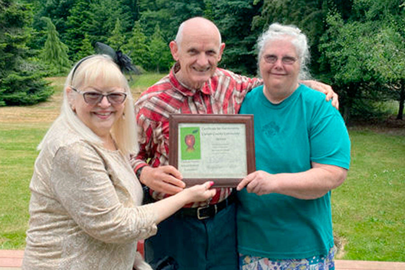 Lora Brabant, on left, presents the Clallam County School Retirees Association’s 2021 Community Service Award to Ray and Ginni Weigel, also pictured is Daisy, the service dog. 

The Weigels were recognized for their support of the community through children’s book drives, cleaning trails, tutoring within the Port Angeles School District and other volunteer services.