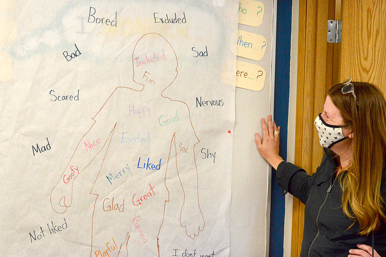 Swan School staffer April Thompson admires a feelings illustration kept inside Emily Gohn’s classroom, which has become a storage room since Swan went all outdoors. (Diane Urbani de la Paz/Peninsula Daily News)