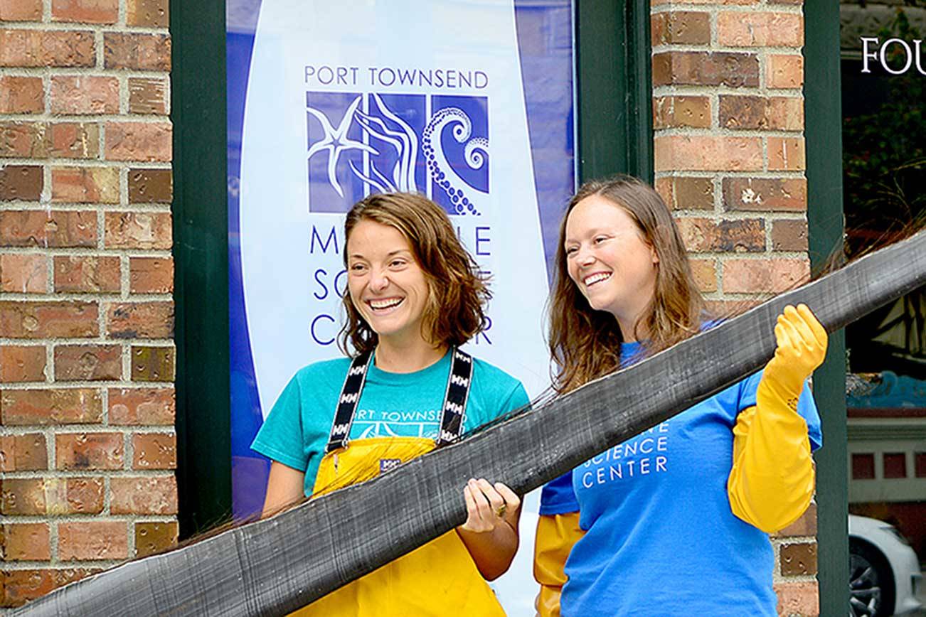 Holding a piece of baleen from a bowhead whale, Port Townsend Marine Science Center exhibit and outreach specialist Mandi Johnson, left, and aquarium specialist Marley Loomis stand before the center’s newly acquired Flagship Landing building in downtown Port Townsend. (Diane Urbani de la Paz/Peninsula Daily News)