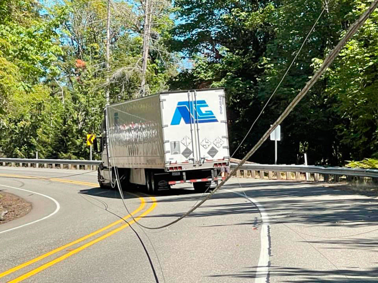 A semi-truck got caught in downed power lines along U.S. Highway 101 at milepost 302 that are believed to have been pulled down by an overheight vehicle Wednesday afternoon. (Photo Courtesy of Brinnon Fire Department)