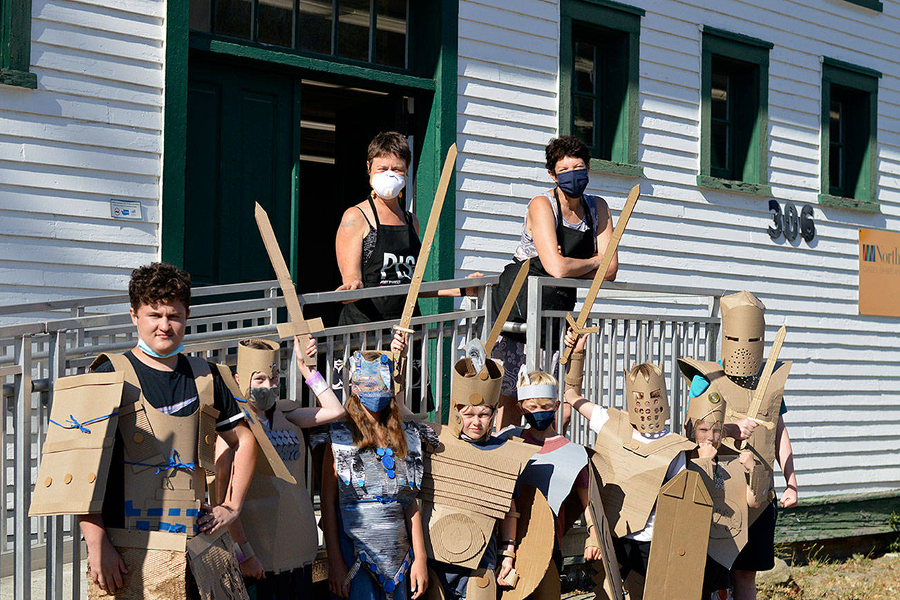 Teaching artists Margie McDonald, at left on the porch, and Michele Soderstrom led a four-afternoon course on building superhero armor for youngsters at the Northwind Art school at Fort Worden State Park in July. Their graduates are Callum Johnson, 14, Kaladry Groenig, Satria McKnight and Owen Griffith, all 11, Reid Armstrong, 10, Caleb Armstrong, 9, Byron Eisele, 8, and Nigel Groenig, 13. (Diane Urbani de la Paz/Peninsula Daily News)