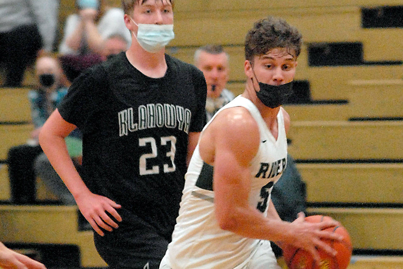 Port Angeles' Chase Cobb, front, makes his way past Klahowya's Robbie Slater in a game last March at Port Angeles High School. Masks will not be required for vaccinated athletes playing high-risk indoor sports such as basketball and wrestling this winter. Non-vaccinated athletes must mask and pass twice weekly COVID screening. (Keith Thorpe/Peninsula Daily News)