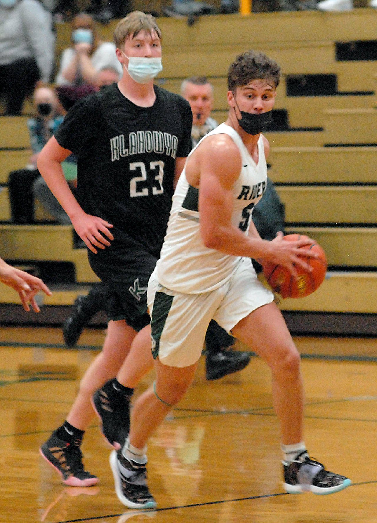 Port Angeles’ Chase Cobb, front, makes his way past Klahowya’s Robbie Slater in a game last March at Port Angeles High School. Masks will not be required for vaccinated athletes playing high-risk indoor sports such as basketball and wrestling this winter. Non-vaccinated athletes must mask and pass twice-weekly COVID screenings. (Keith Thorpe/Peninsula Daily News)