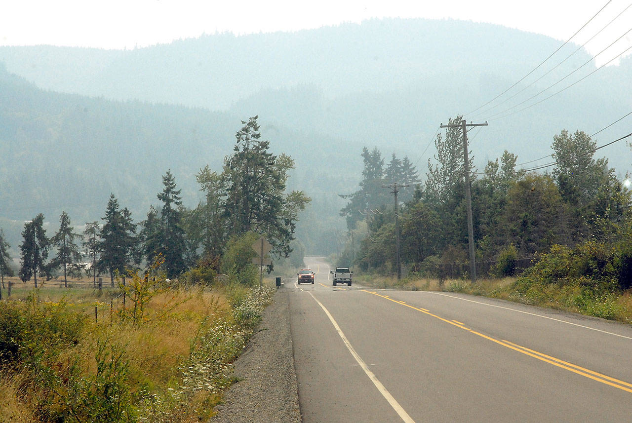 Vehicles make their way down Laird Road west of Port Angeles as a layer of smoke shrouds the Olympic Foothills and the surrounding lowlands on Thursday. (Keith Thorpe/Peninsula Daily News)