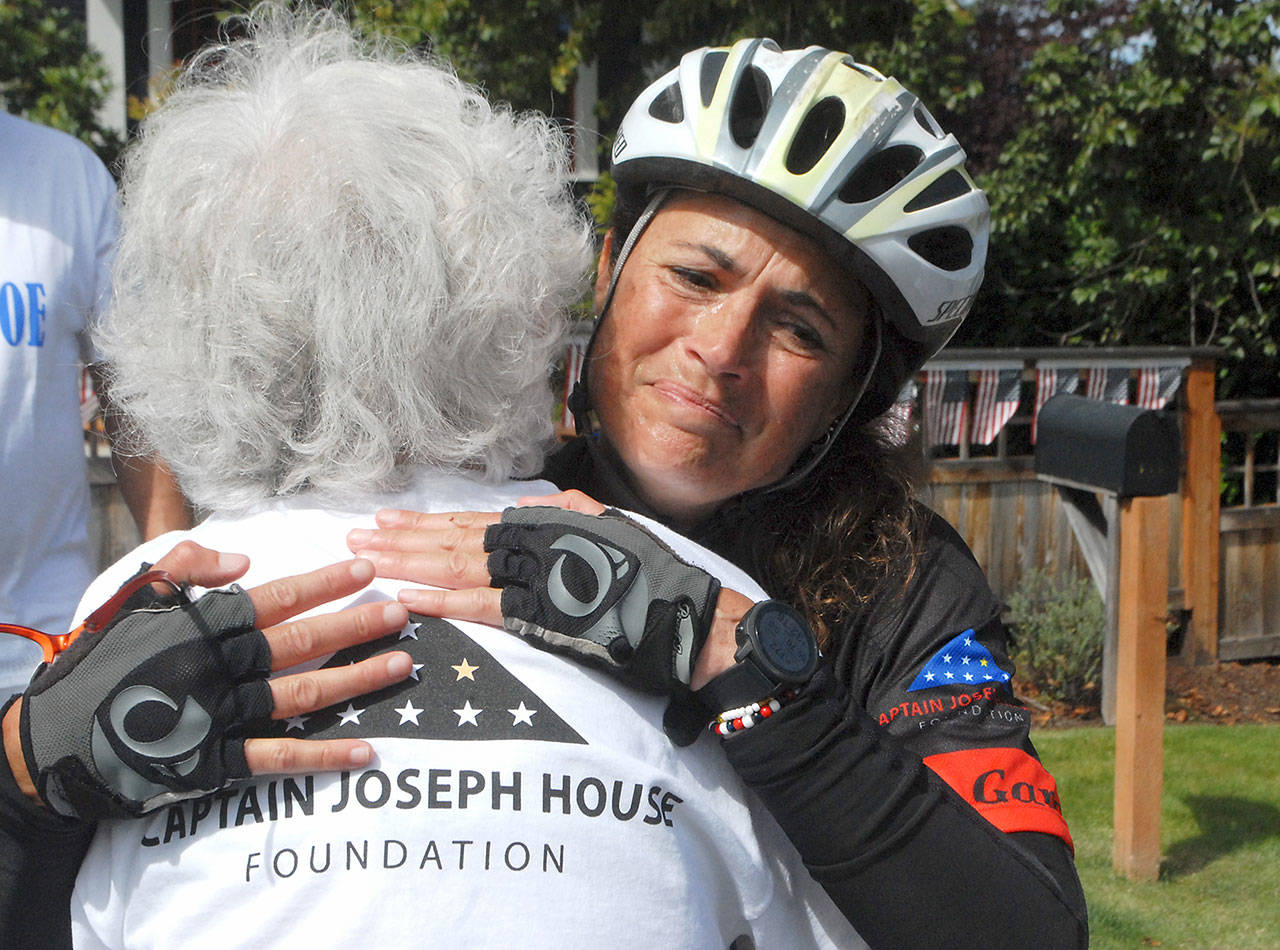 Special education kindergarten teacher Amy DelaBarre of Port Angeles gives an emotional hug to Betsy Schulz, founder of the Captain Joseph House Foundation in Port Angeles, after DelaBarre completes the bicycle portion of “Run for Joe,” a solo triathlon on Saturday to raise funds in support of Gold Star families who have lost loved ones in military action. The Captain Joseph House, a former bed and breakfast, which was converted to give respite to military families, is named for Schultz’s son, Joseph Schultz, who was killed in action in Afghanistan on May 29, 2011. (Keith Thorpe/Peninsula Daily News)