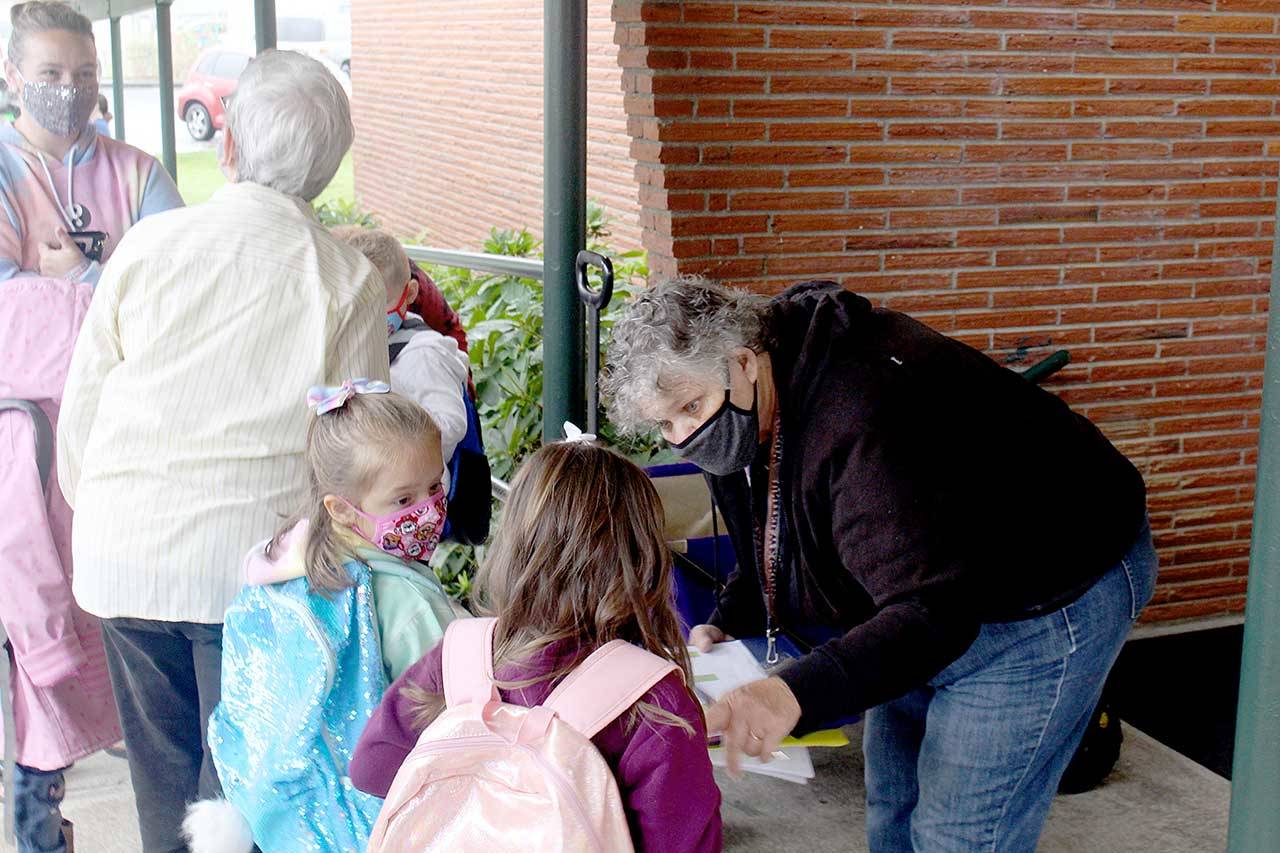 Paraeducator Ginni Beard, right, hands out breakfast bags to kindergarten students during the first day of school for Quilcene School District. Quilcene and Brinnon school districts both began instruction Monday, with COVID-19 prevention protocols, including mask wearing and social distancing for students and staff. (Zach Jablonski/Peninsula Daily News)