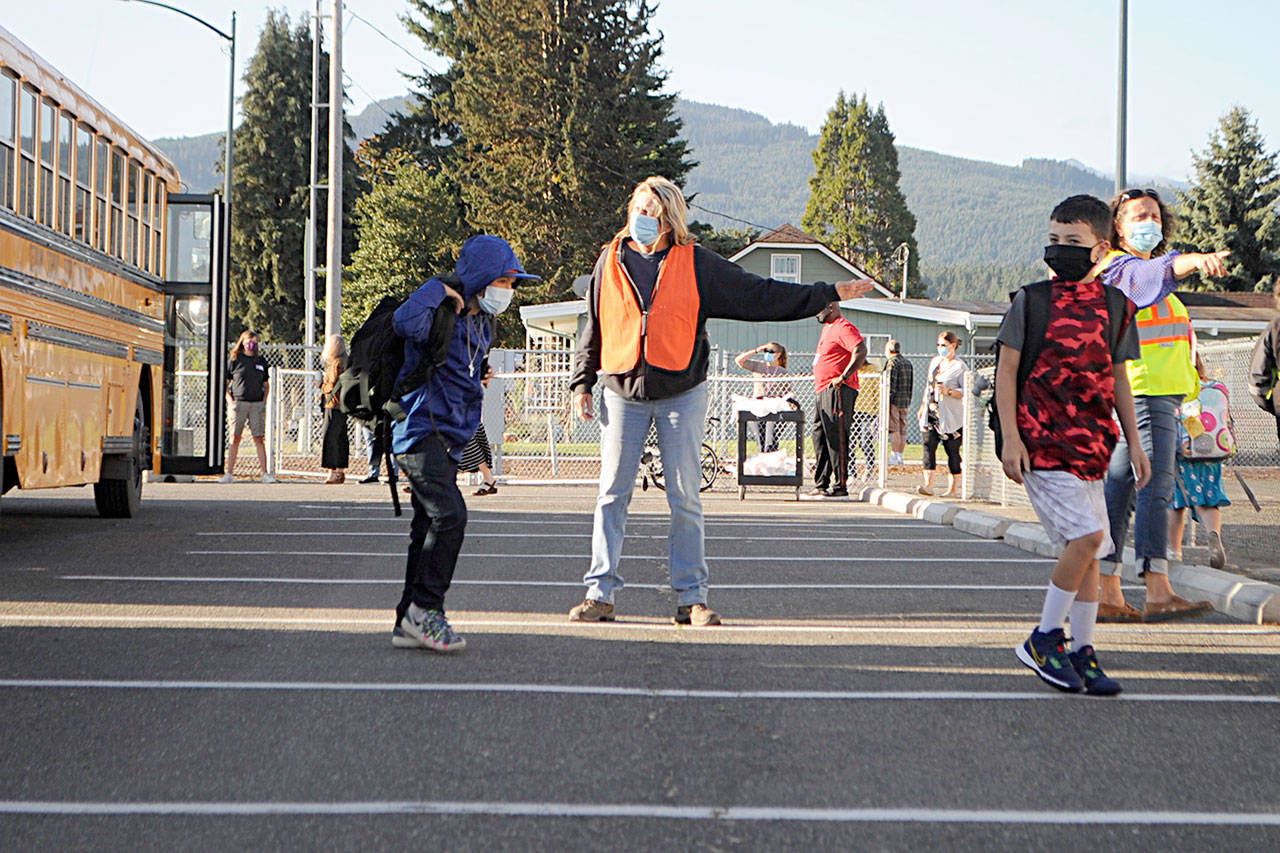 Bus driver Veronica Brenner, center, and paraeducator Liz Joers direct students to classrooms at Helen Haller Elementary and buses to Greywolf Elementary on Wednesday morning for the first day of school. (Matthew Nash/Olympic Peninsula News Group)