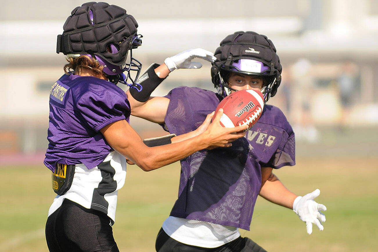 Sequim senior quarterback Kobe Applegate, left, prepares to hand off the football to Aiden Gockerell during a recent practice. The Wolves visit Forks tonight at 7 p.m. in the season opener for each school. (Michael Dashiell/Olympic Peninsula News Group)