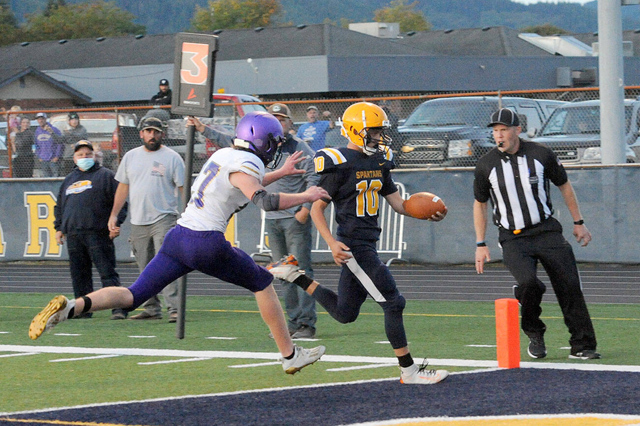 Lonnie Archibald/for Peninsula Daily News
Forks quarterback Logan Olson outruns Sequim's Mason King for a touchdown in the second quarter of the Spartans' 56-28 season-opening win over the Wolves.