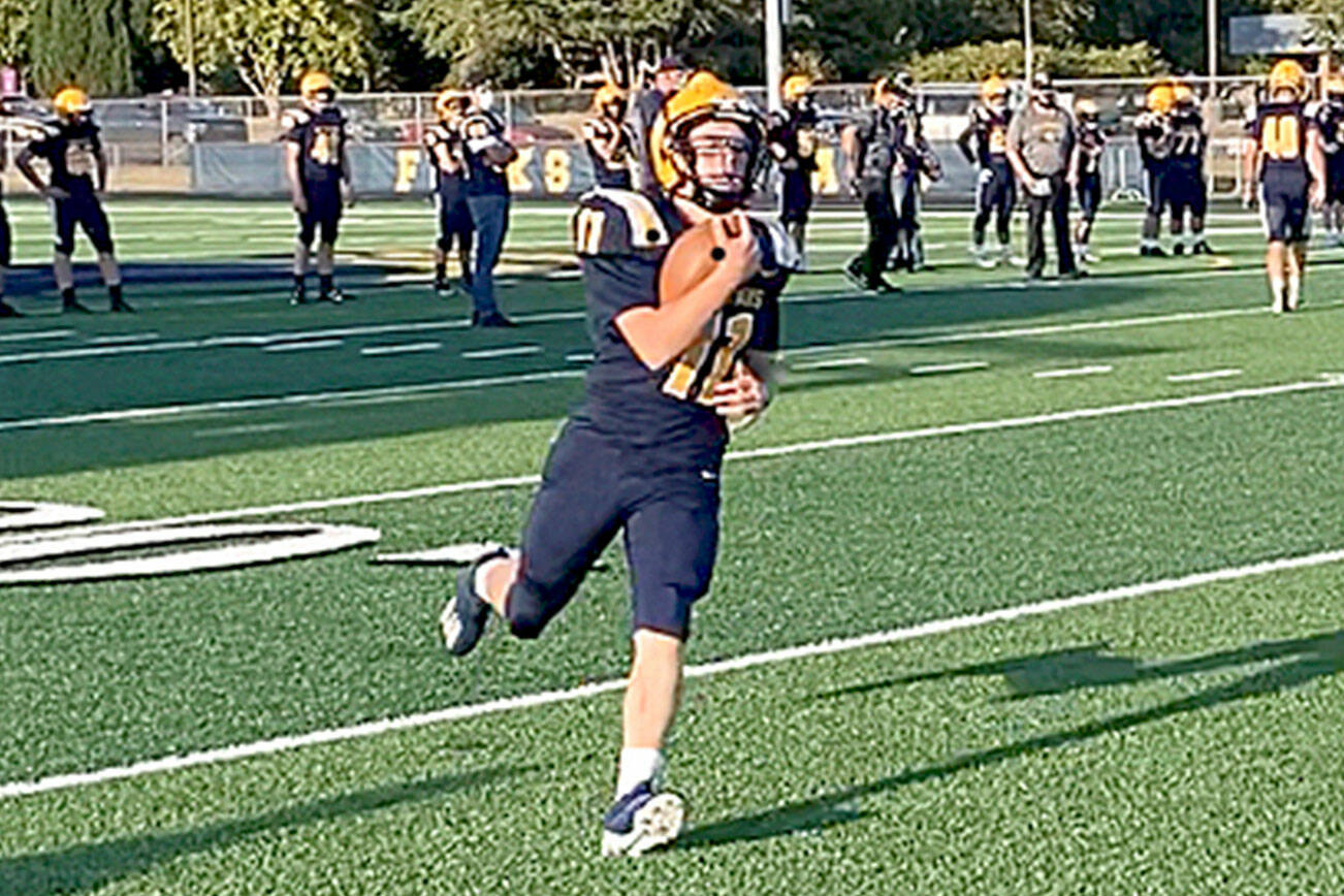 Forks' Kaleb Blanton runs with the ball during pregame warmups before the Spartans' home opener with Sequim last Friday. Blanton and Forks debuted new home uniforms with gold and white shoulder stripes and gold numbers in the game. (Michael Carman/Peninsula Daily News)