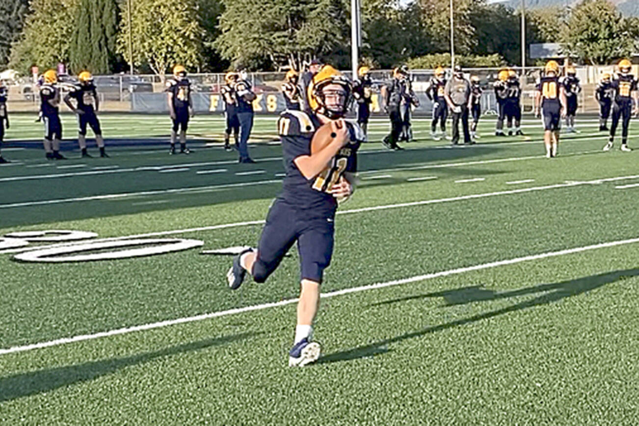 Michael Carman/Peninsula Daily News Forks’ Kaleb Blanton runs with the ball during pregame warmups before the Spartans’ home opener with Sequim last Friday. Blanton and Forks debuted new home uniforms with gold and white shoulder stripes and gold numbers in the game.