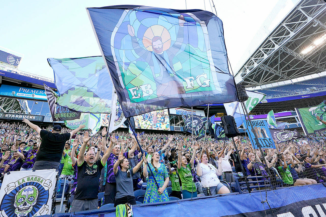 FILE - In this July 25, 2021, file photo, members of the Emerald City Supporters and other fans wave flags and cheer before an MLS soccer match between the Seattle Sounders and Sporting Kansas City in Seattle. Fans attending most pro sporting events in Seattle will soon be required to show proof they’ve been vaccinated against COVID-19 or that they’ve tested negative for the virus. The NFL’s Seahawks, MLS’s Sounders, NHL’s Kraken and the University of Washington all announced updated policies Tuesday, Sept. 7, 2021, for fans attending games this season. (AP Photo/Ted S. Warren, File)