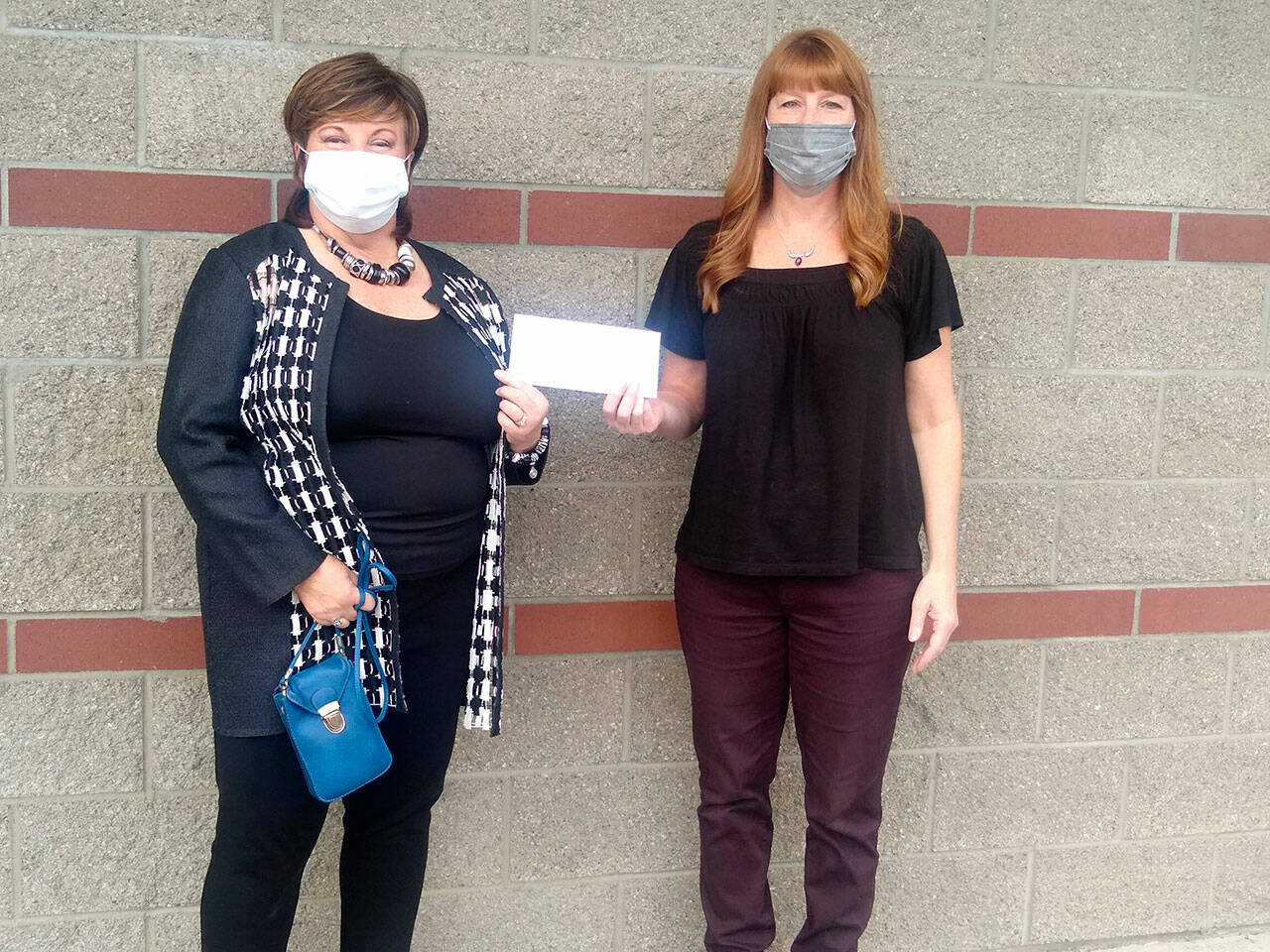 LuAnne Hinkle, left, of the Olympic Peninsula Humane Society, receives a check from Ginger Rushton of the home health department at Jim’s Pharmacy in Port Angeles.