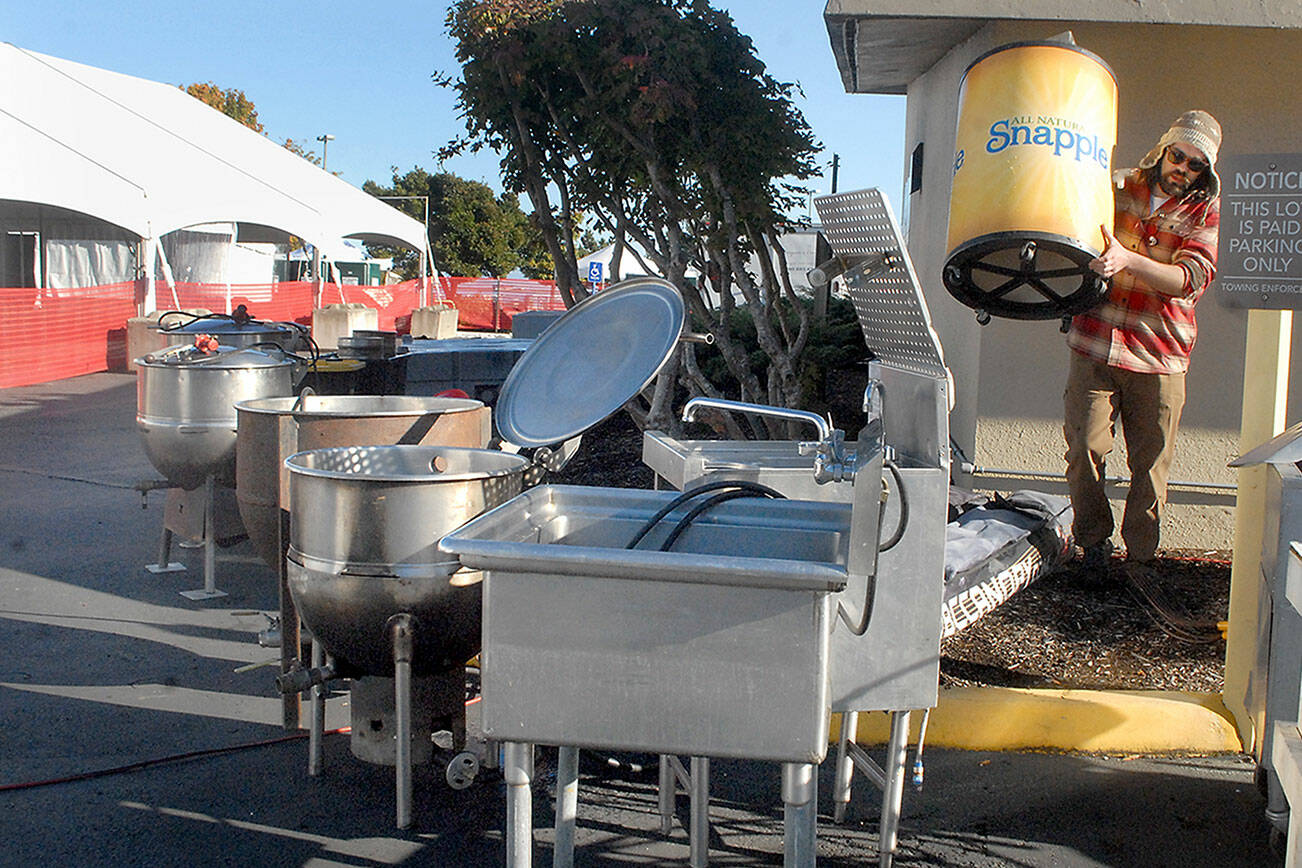 Keith Thorpe/Peninsula Daily News
Quinton Chastain of Olympia carries an insulated barrel on Thursday while setting up an outdoor kitchen for this weekend's Dungeness Crab and Seafood Festival near the Port Angeles waterfront. The three-day festival begins today