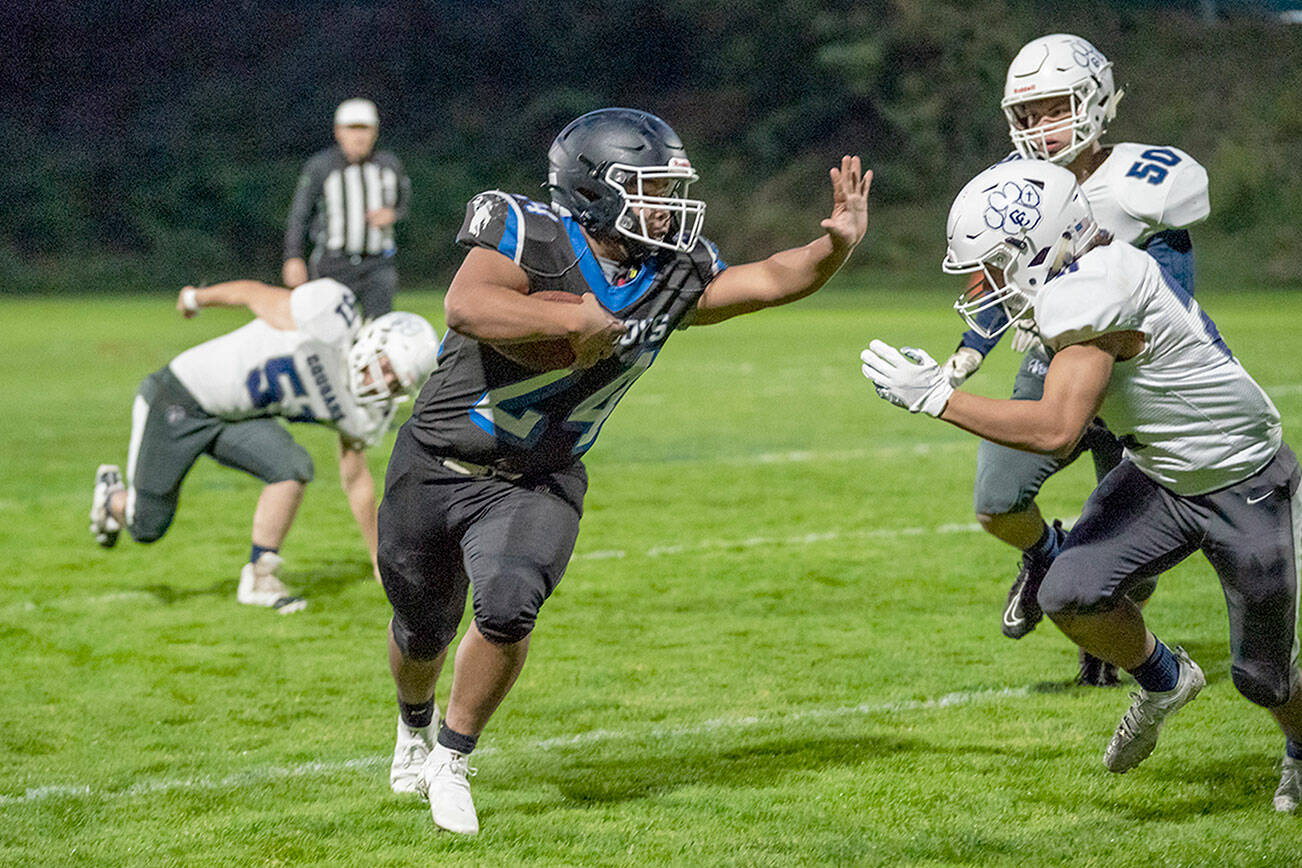 Steve Mullensky/for Peninsula Daily News

East Jefferson Rival Anson Jones rushes around Cougars Brayden Metcalf (50) and Torin Carpenter (51) during a Friday night game played in Memorial Field in Port Townsend.