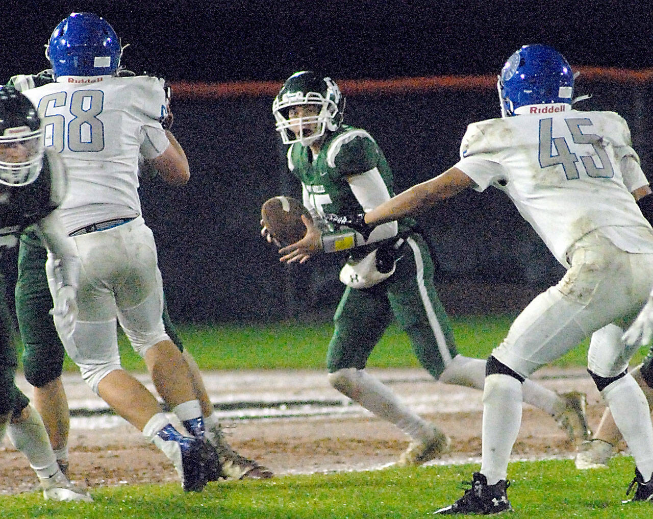 Port Angeles quarterback Parker Nickerson, center, looks downfield as Olympic’s Jacob Gesell, left, and Alexander Larson, right, close in on Friday night at Port Angeles Civic Field. (Keith Thorpe/Peninsula Daily News)