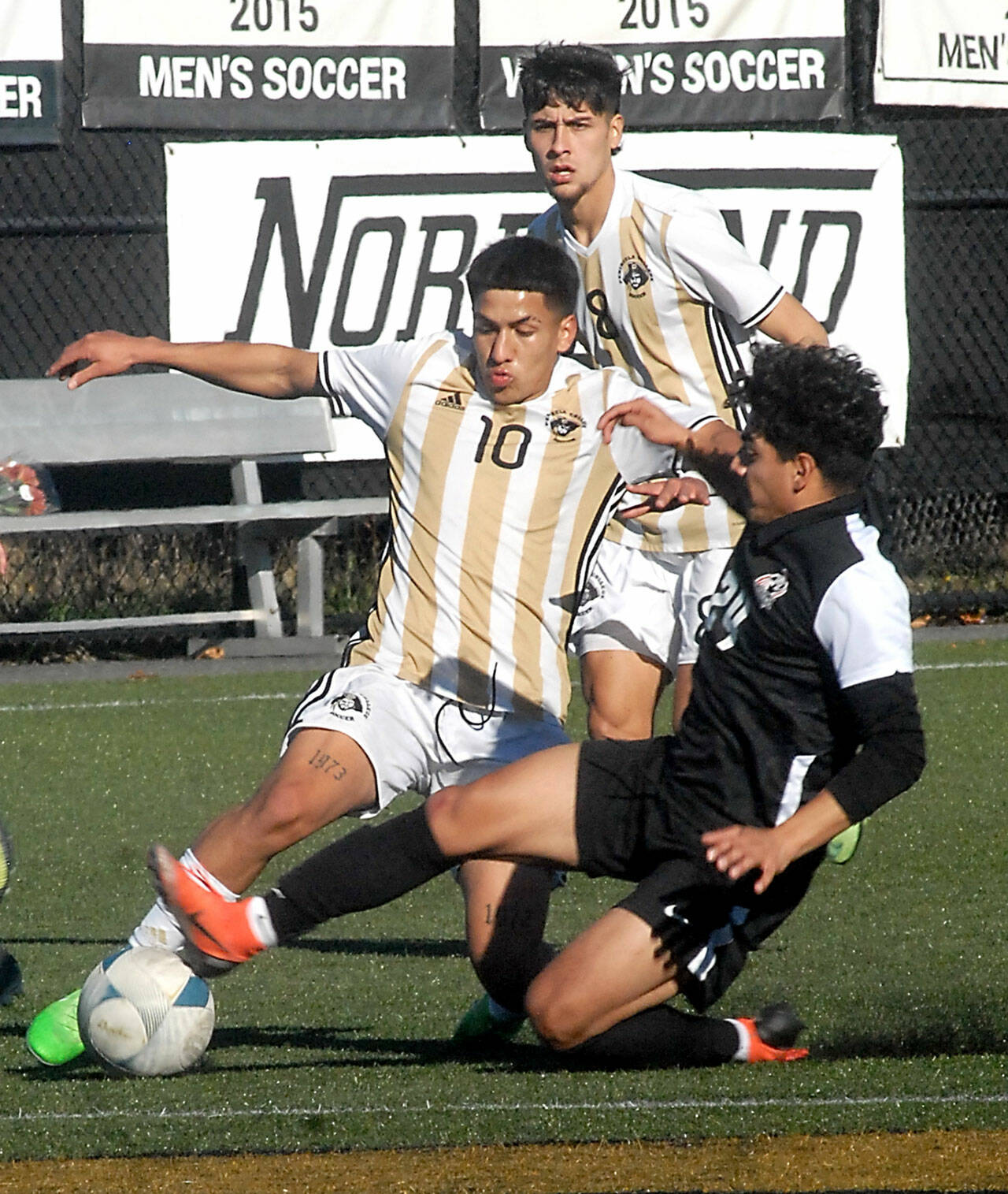 Peninsula’s Fernando Tavares, center, fights off a tackle by Everett’s Carlos Rodriguez as Tavares’ teammate, Juan Carlos Hernandez, looks on during Saturday’s match at Wally Sigmar Field in Port Angeles. (Keith Thorpe/Peninsula Daily News)