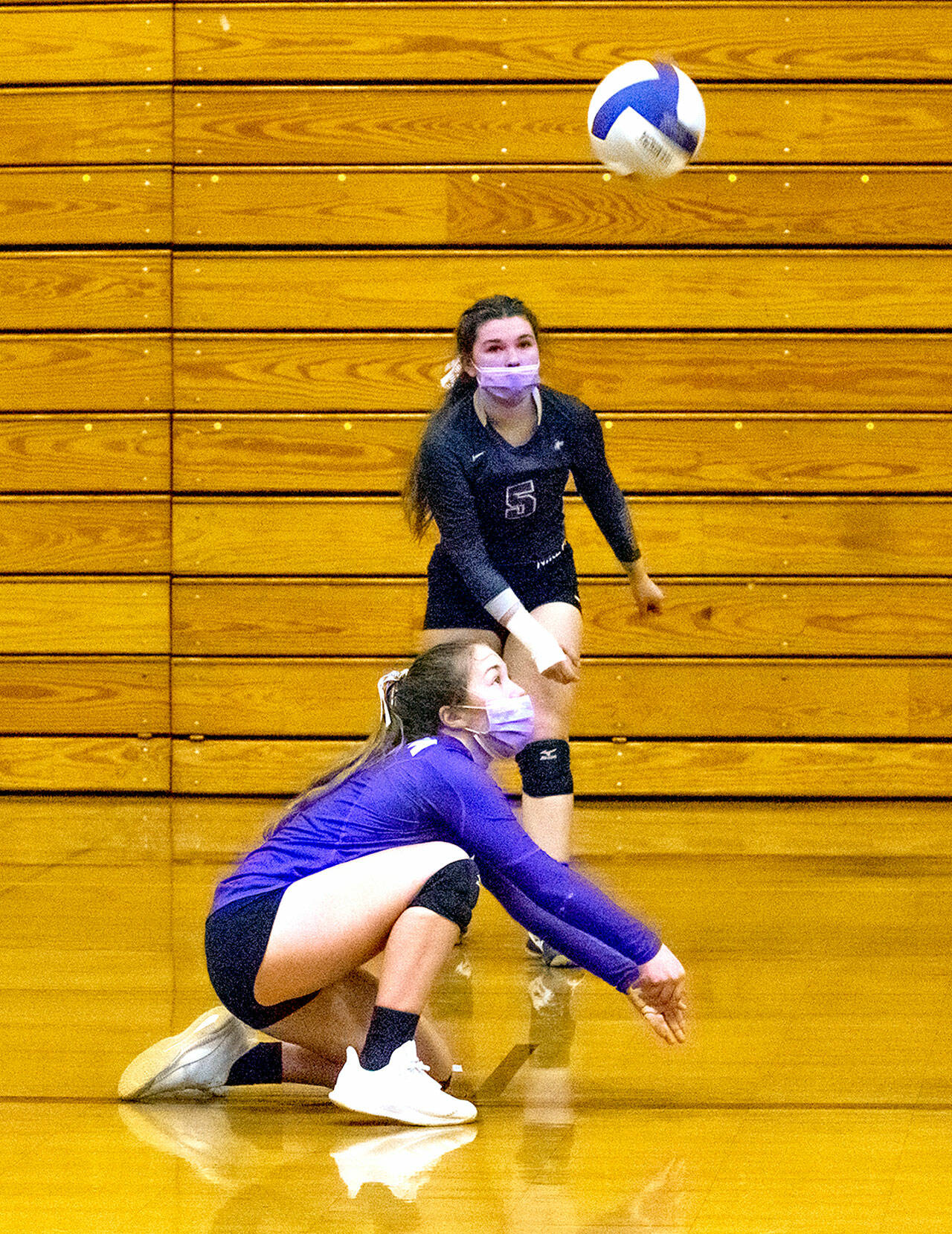 As teammate Allie Gale looks on, Sequim’s Jordan Hegtvedt gets down low for a dig in the Wolves’ 3-1 win over Kingston on Tuesday. (Emily Matthiessen/Olympic Peninsula News Group)