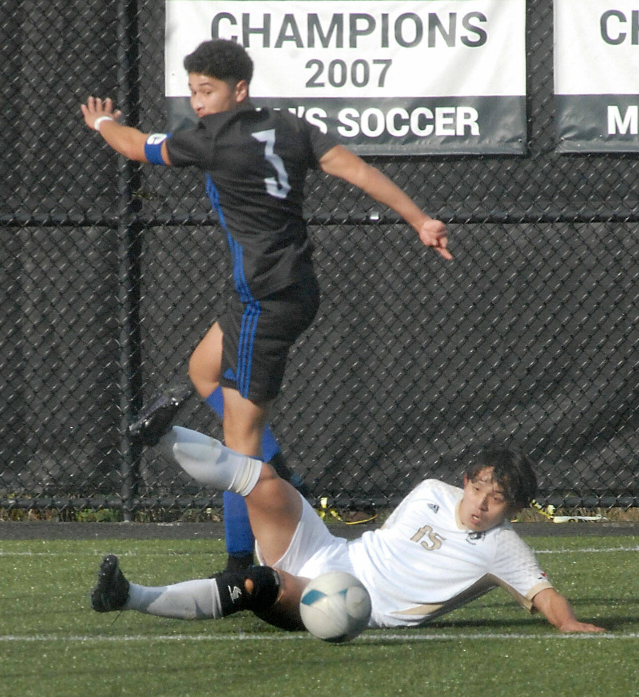 Peninsula’s Chunghwan Lee makes a sliding tackle as Rogue’s Josue Reyes avoids a collision on Saturday in Port Angeles. (Keith Thorpe/Peninsula Daily News)